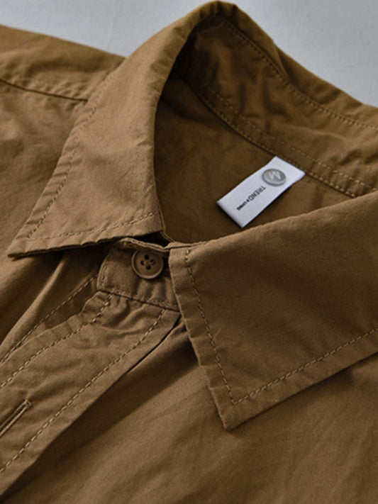 Close-up of a brown shirt collar with a visible brand label on a neutral background