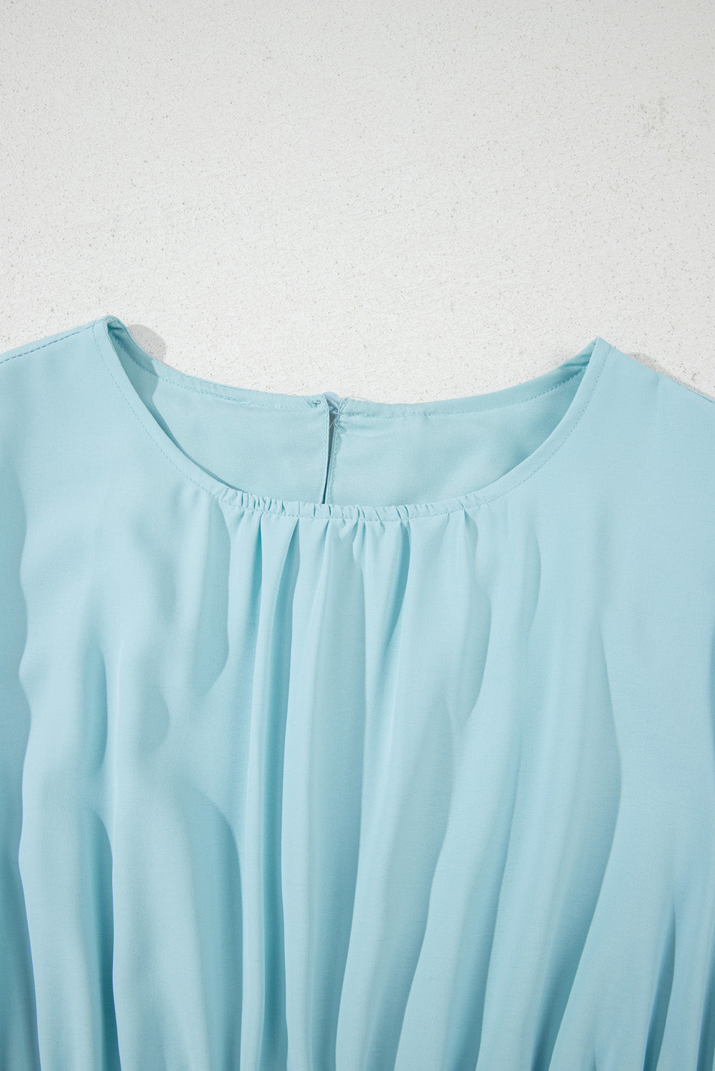 Light blue sleeveless top on a textured white background