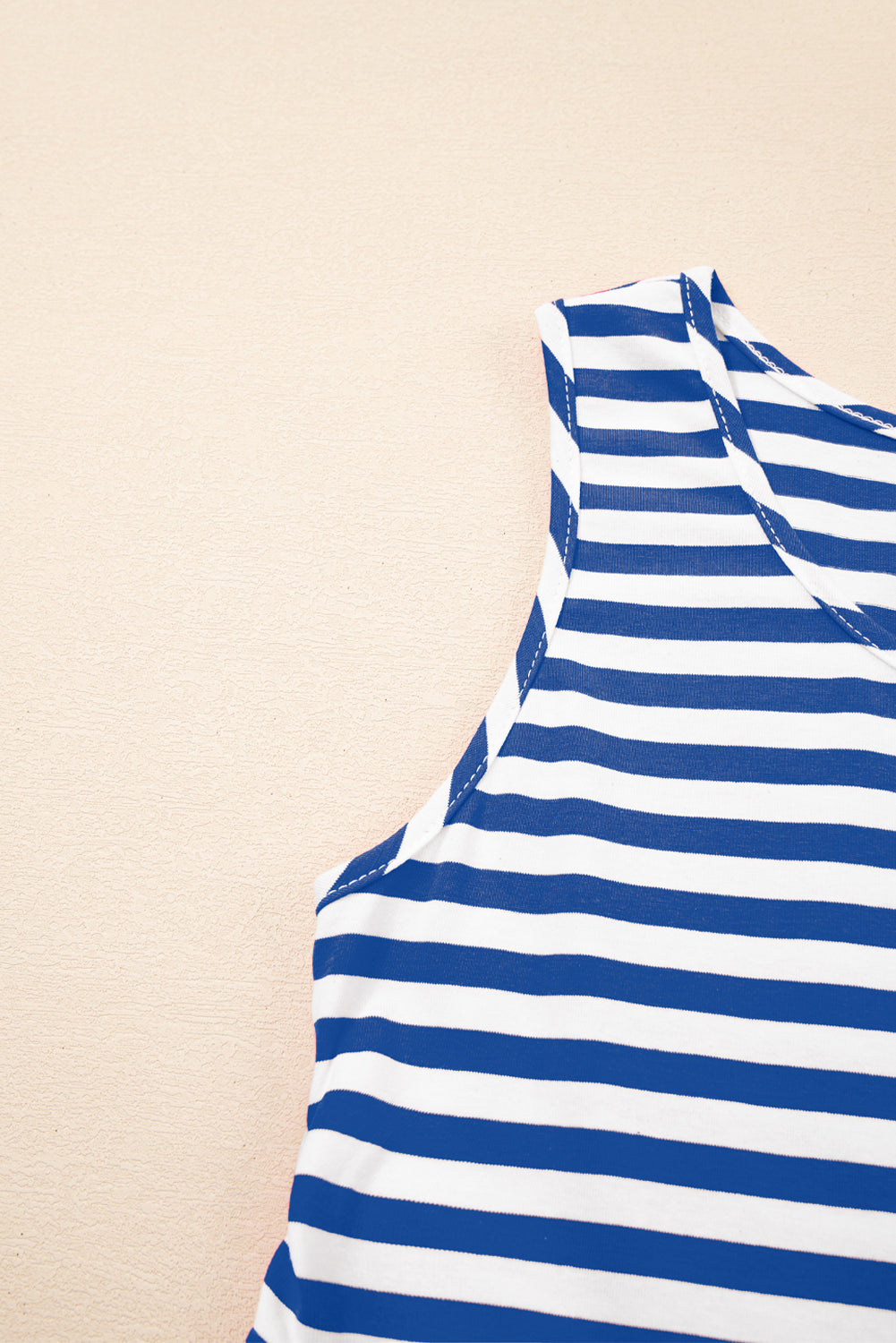 Blue and white striped sleeveless top on a beige background