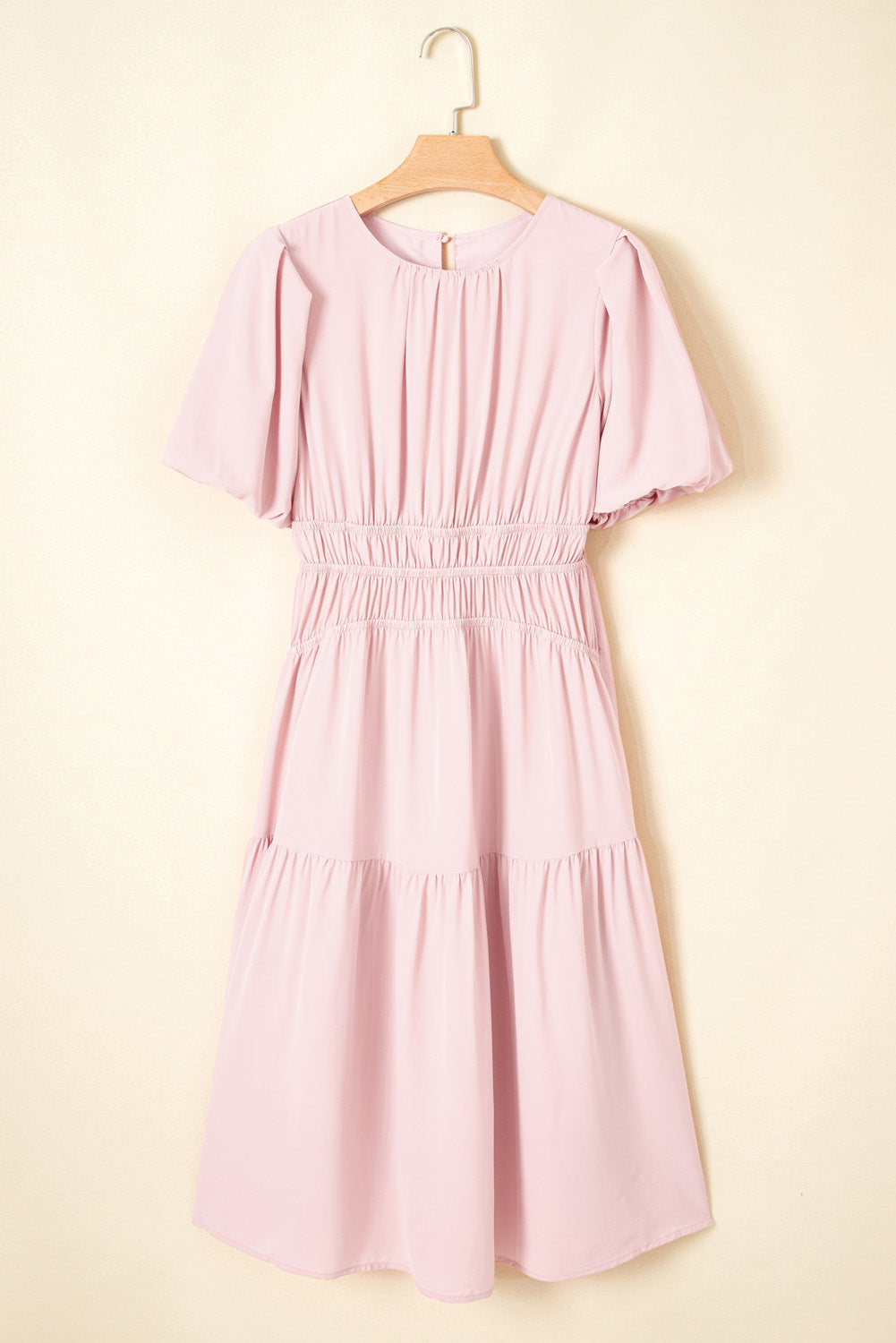 Pink dress on a hanger against a beige background