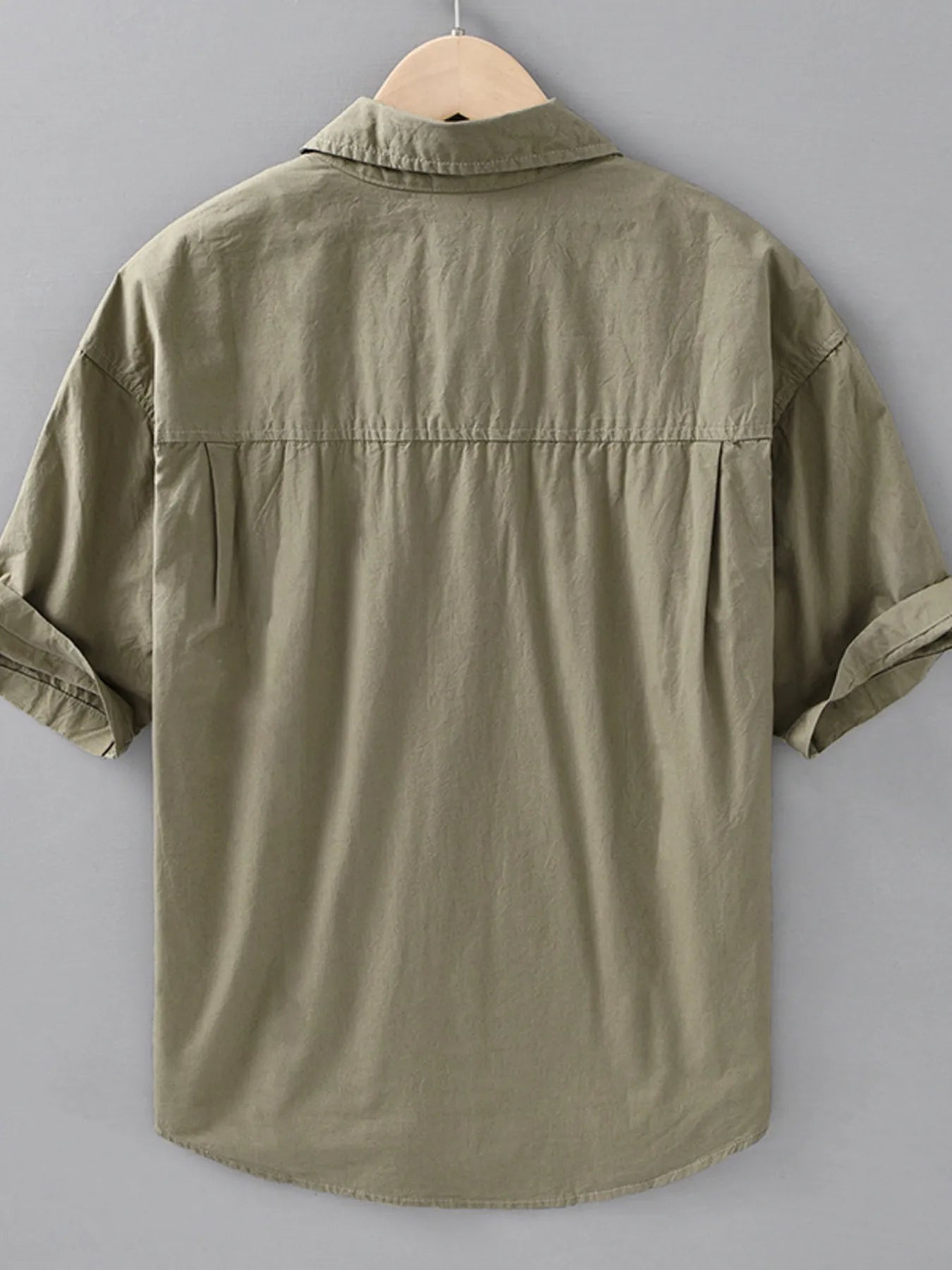 Green short-sleeve shirt on a hanger against a gray background