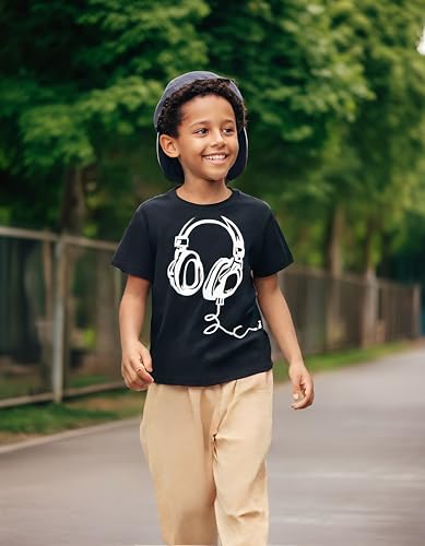 Child wearing a black t-shirt with headphones graphic and beige pants, standing outdoors.