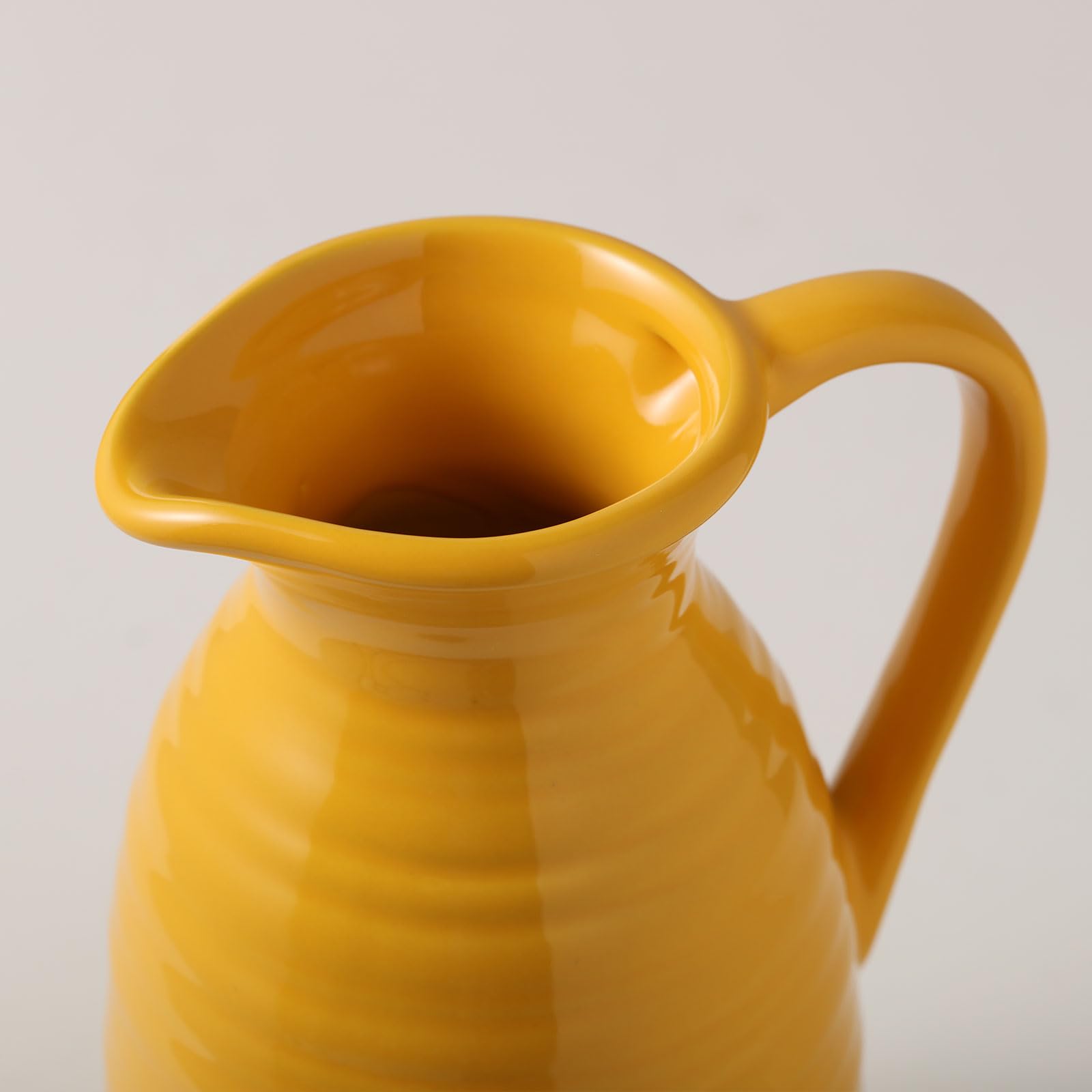 Yellow ceramic pitcher on a light gray background