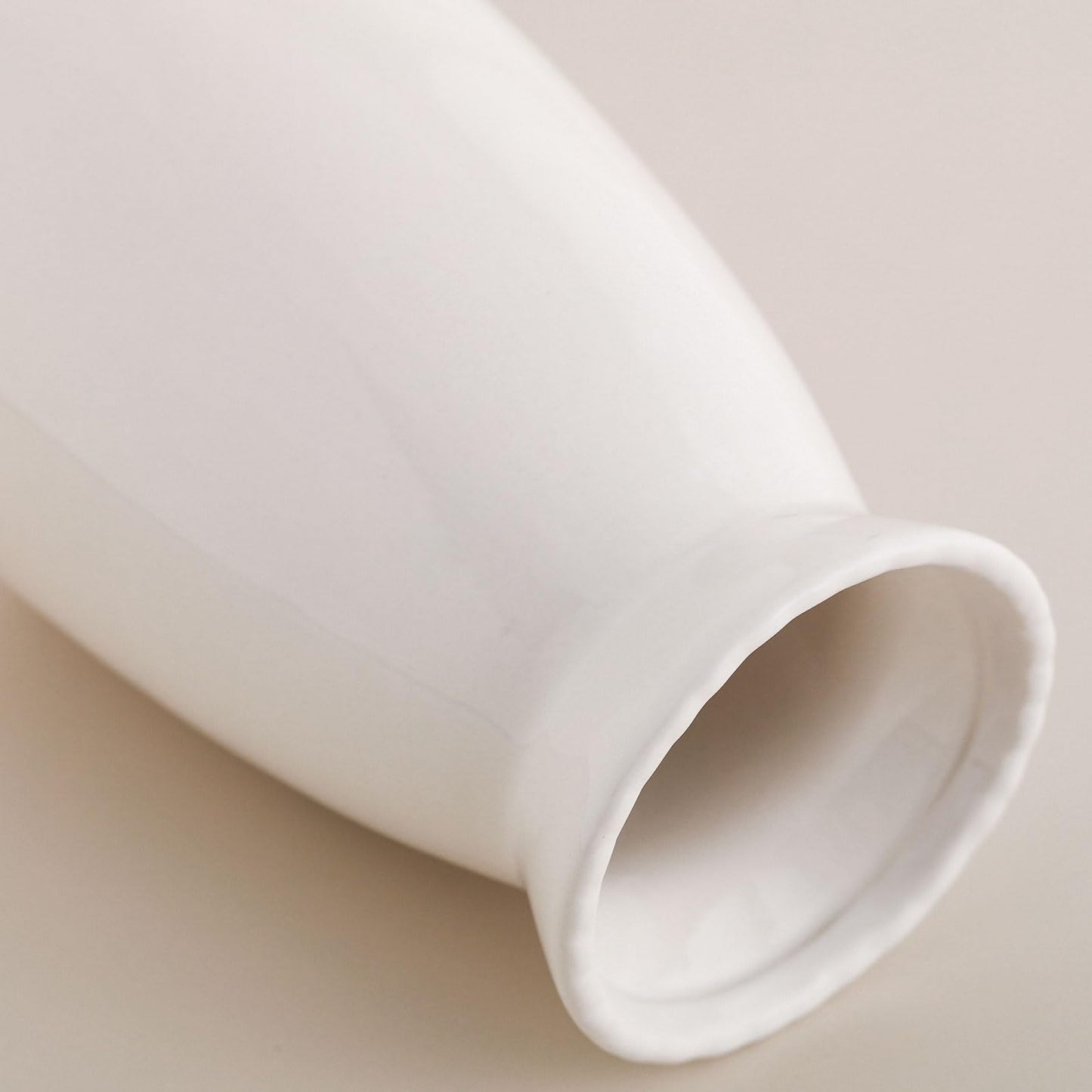 White ceramic vase on a beige background