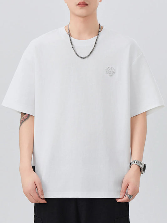 Person wearing a plain white t-shirt with a small logo on a light gray background