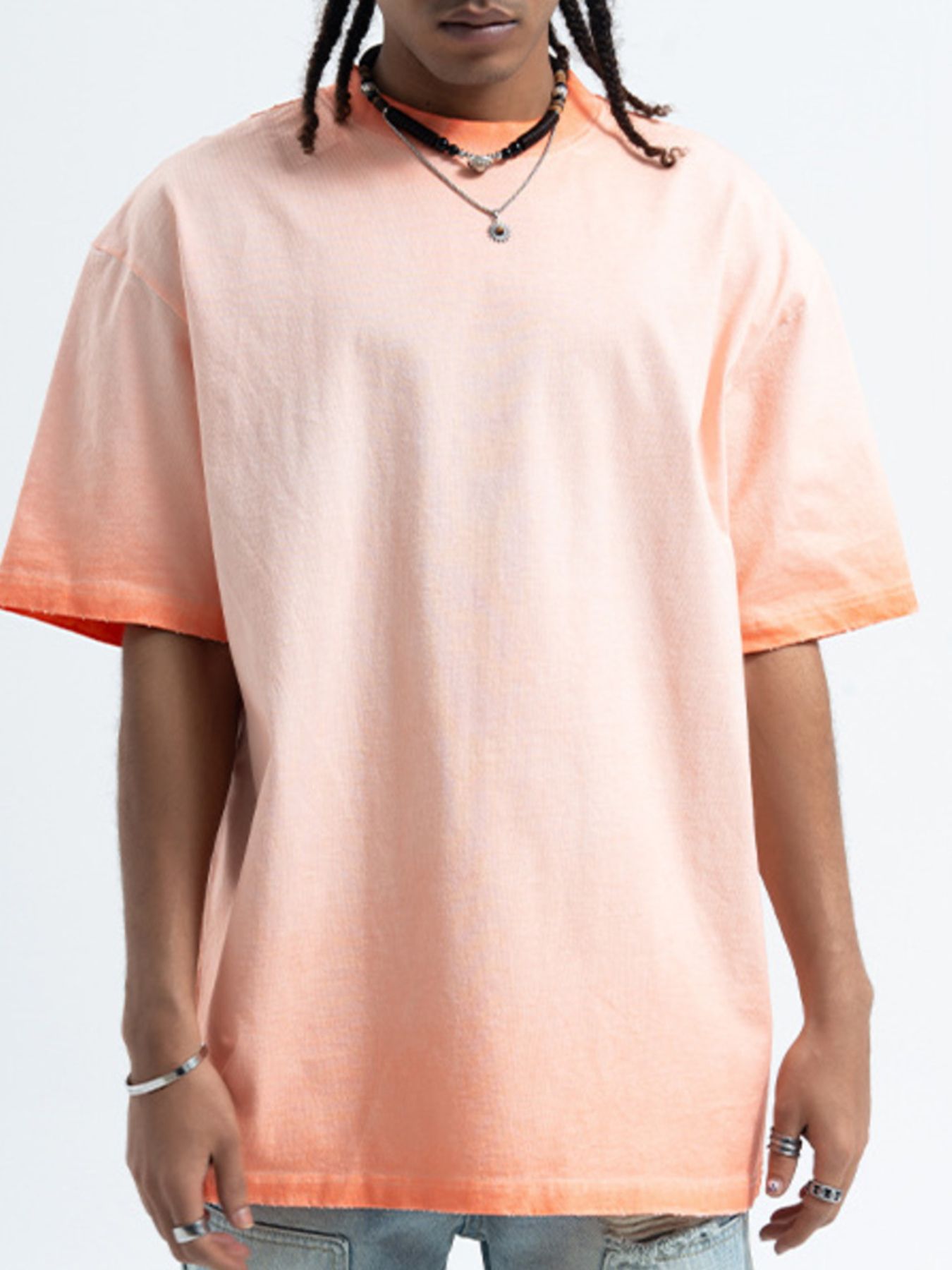 Person wearing a peach-colored t-shirt with a plain background