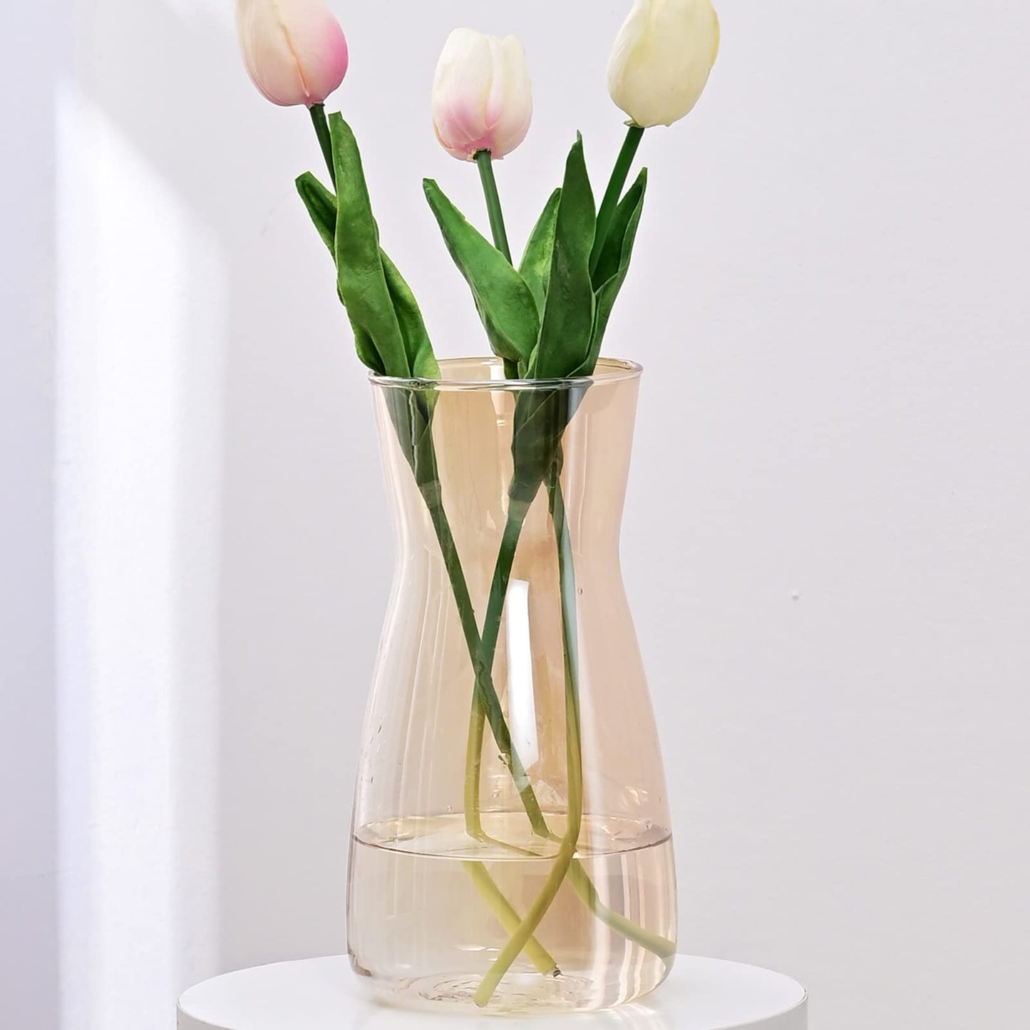 Clear vase with pink and white tulips on a white background