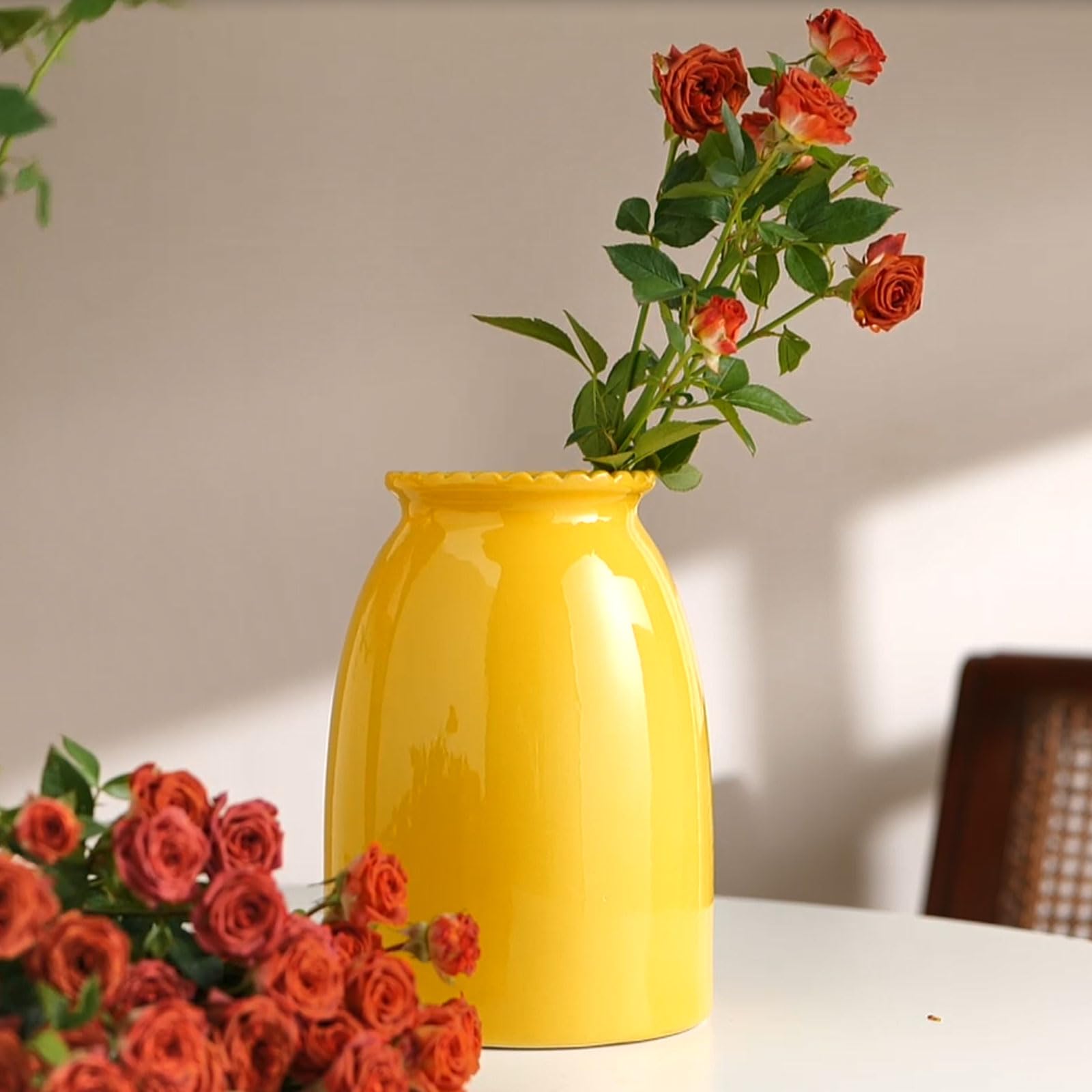 Yellow vase with red roses on a table