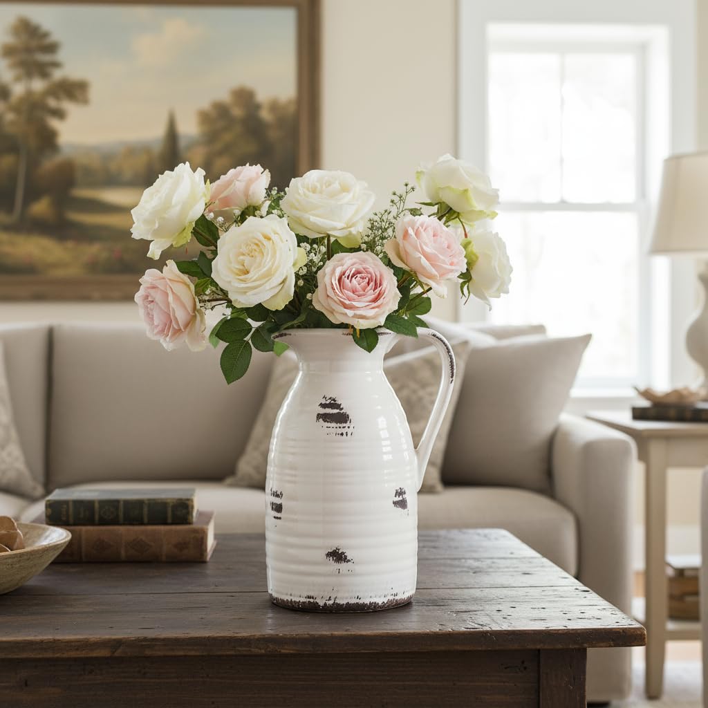 White pitcher vase with pink and white flowers on a wooden table in a living room.