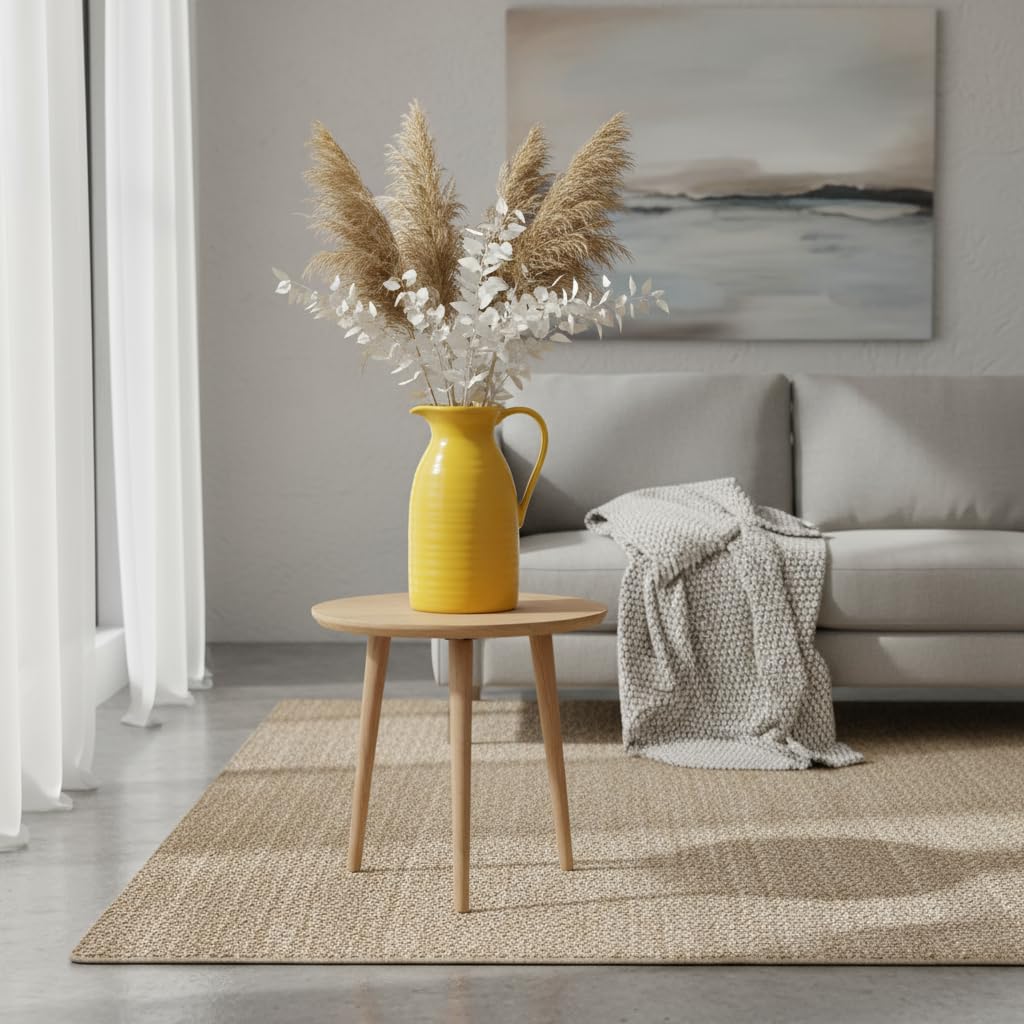 Yellow vase with dried plants on a wooden side table in a living room.