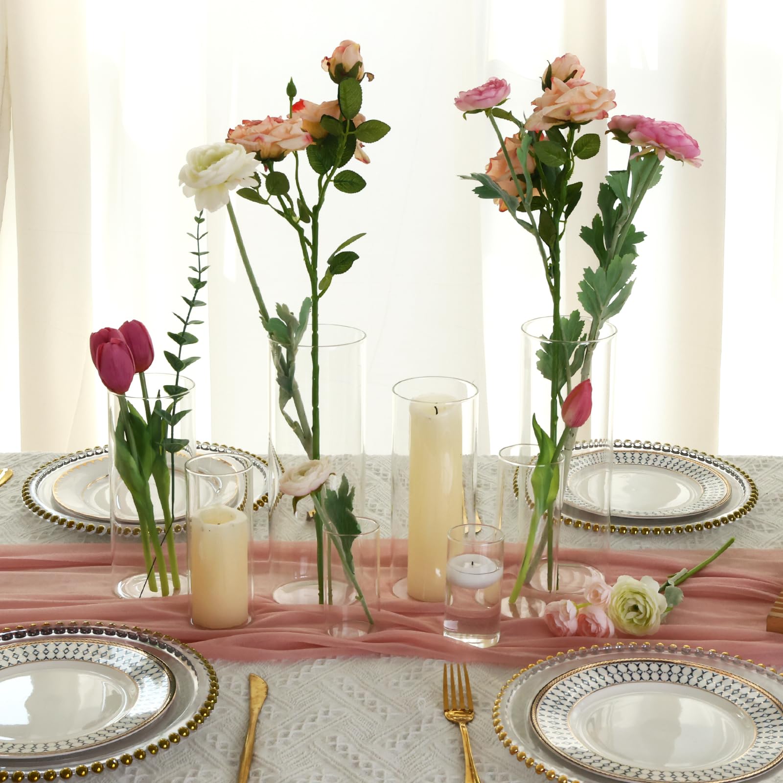 Decorative table setting with flowers, candles, and plates on a light background