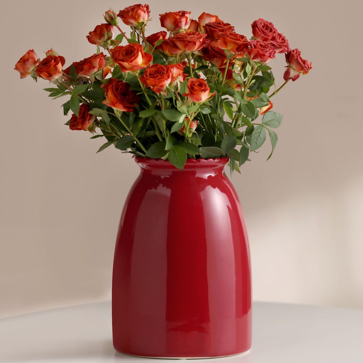Red vase with red roses on a neutral background