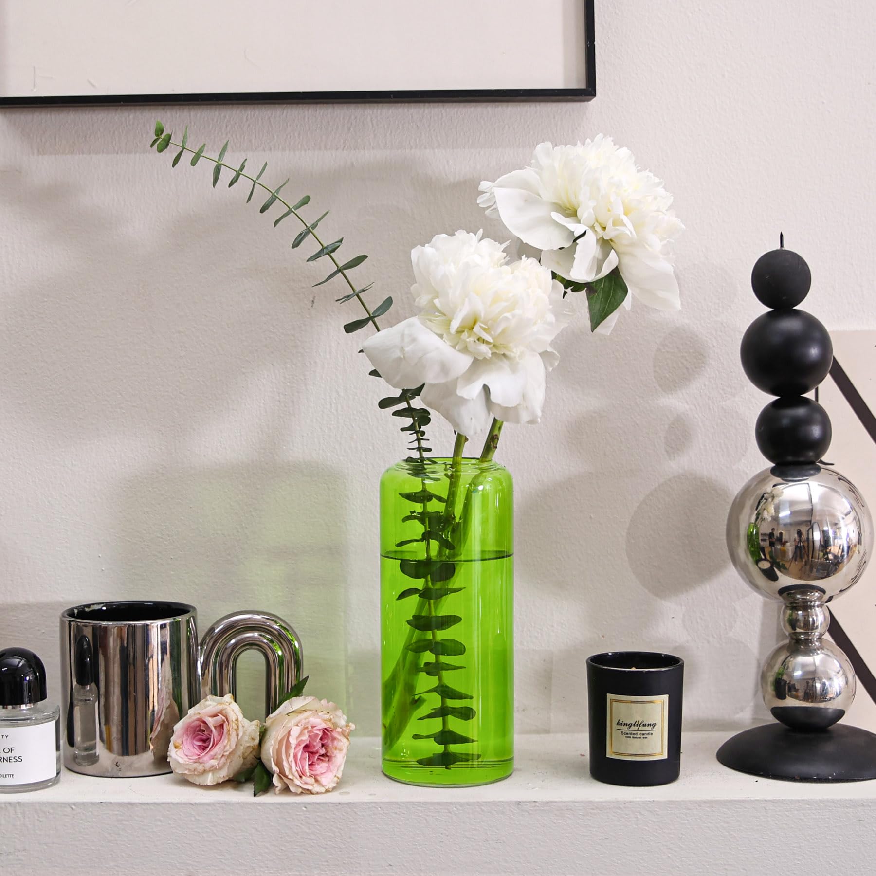 Decorative arrangement with red berries, green leaves, and a vase on a surface.