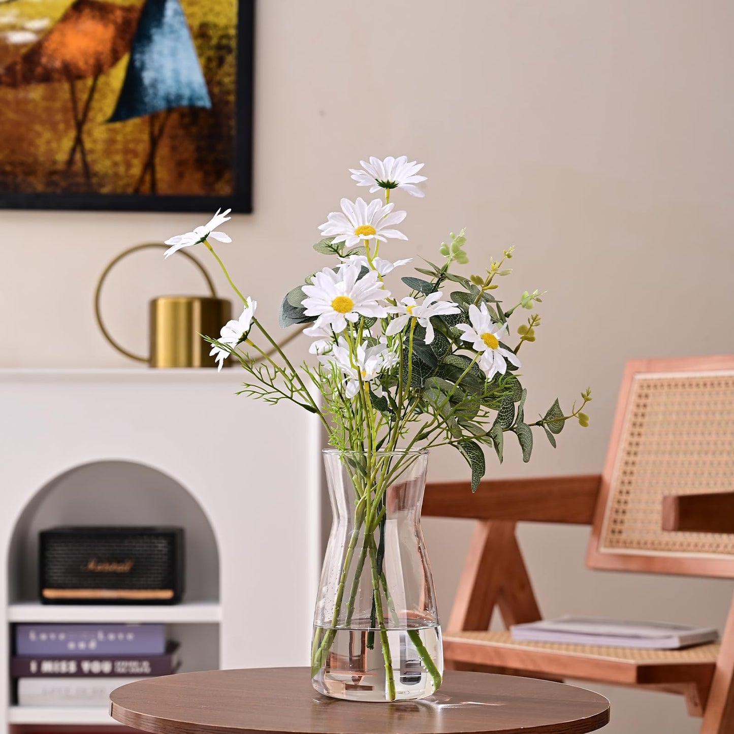 Clear glass vase with daisies on a wooden table in a room setting.