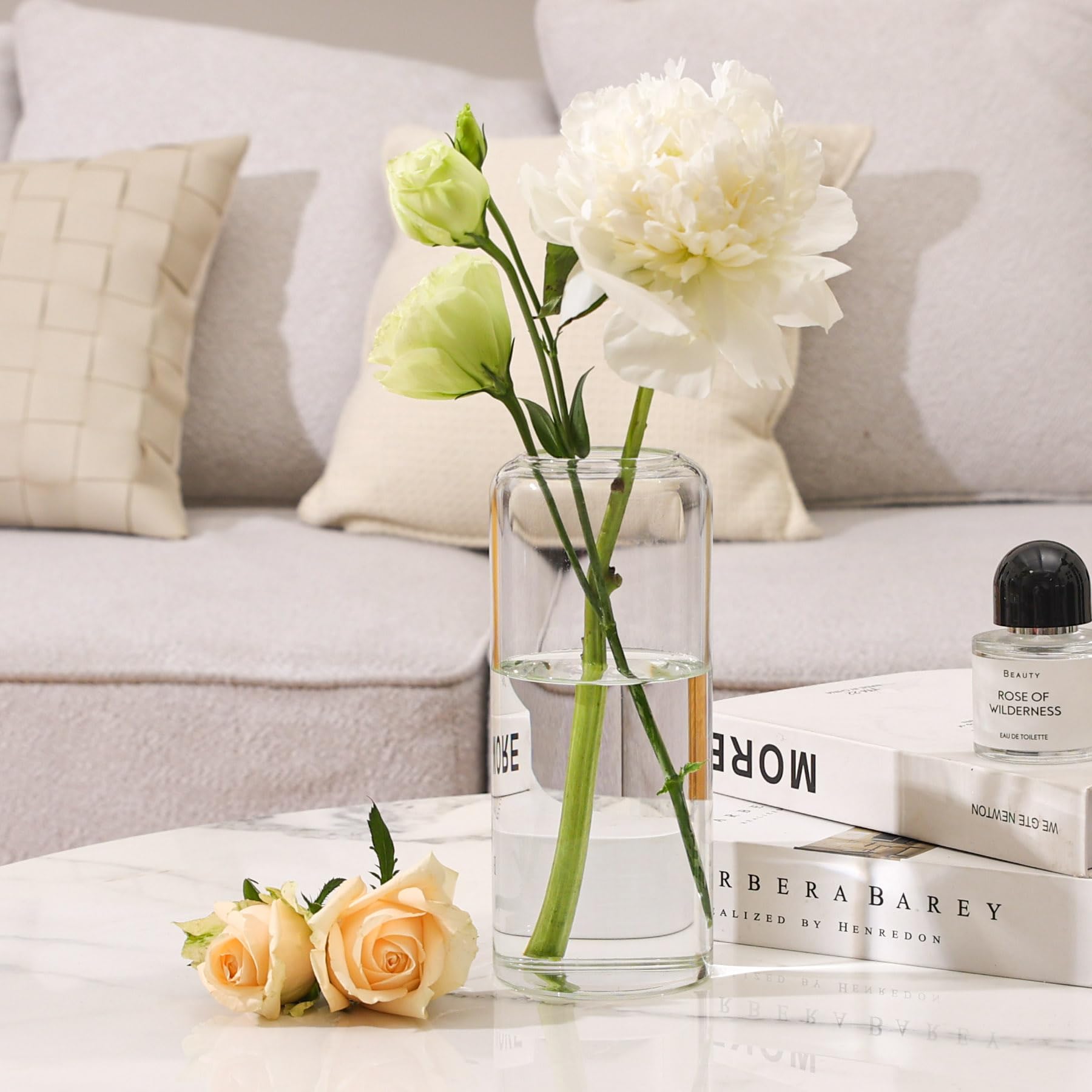 Clear glass vase with flowers on a coffee table in a living room setting.