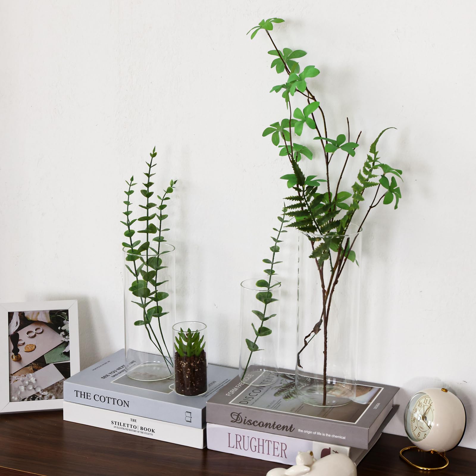 Decorative setup with books, plants, and a clock on a wooden surface.