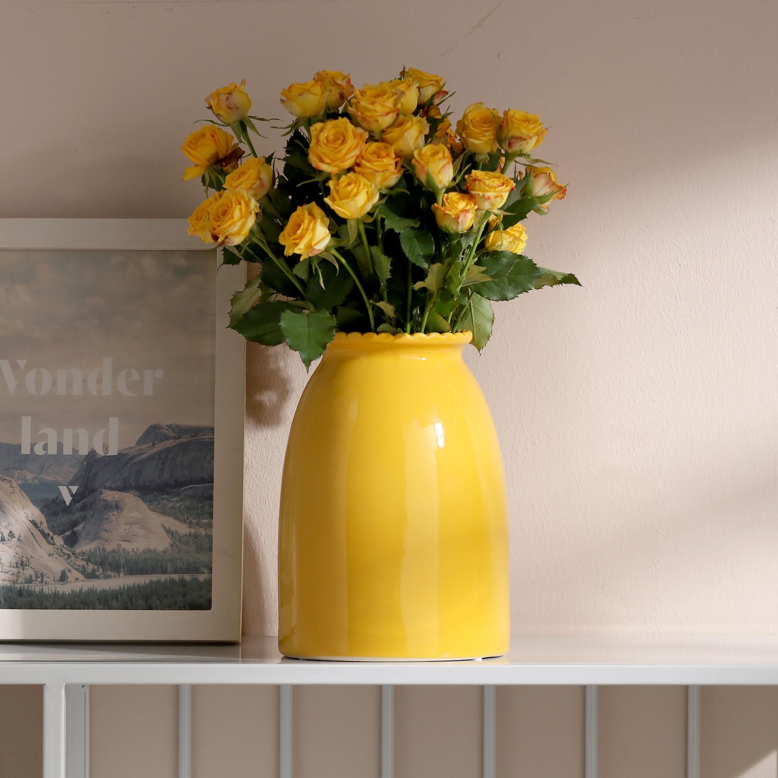 Yellow vase with yellow roses on a shelf against a neutral wall