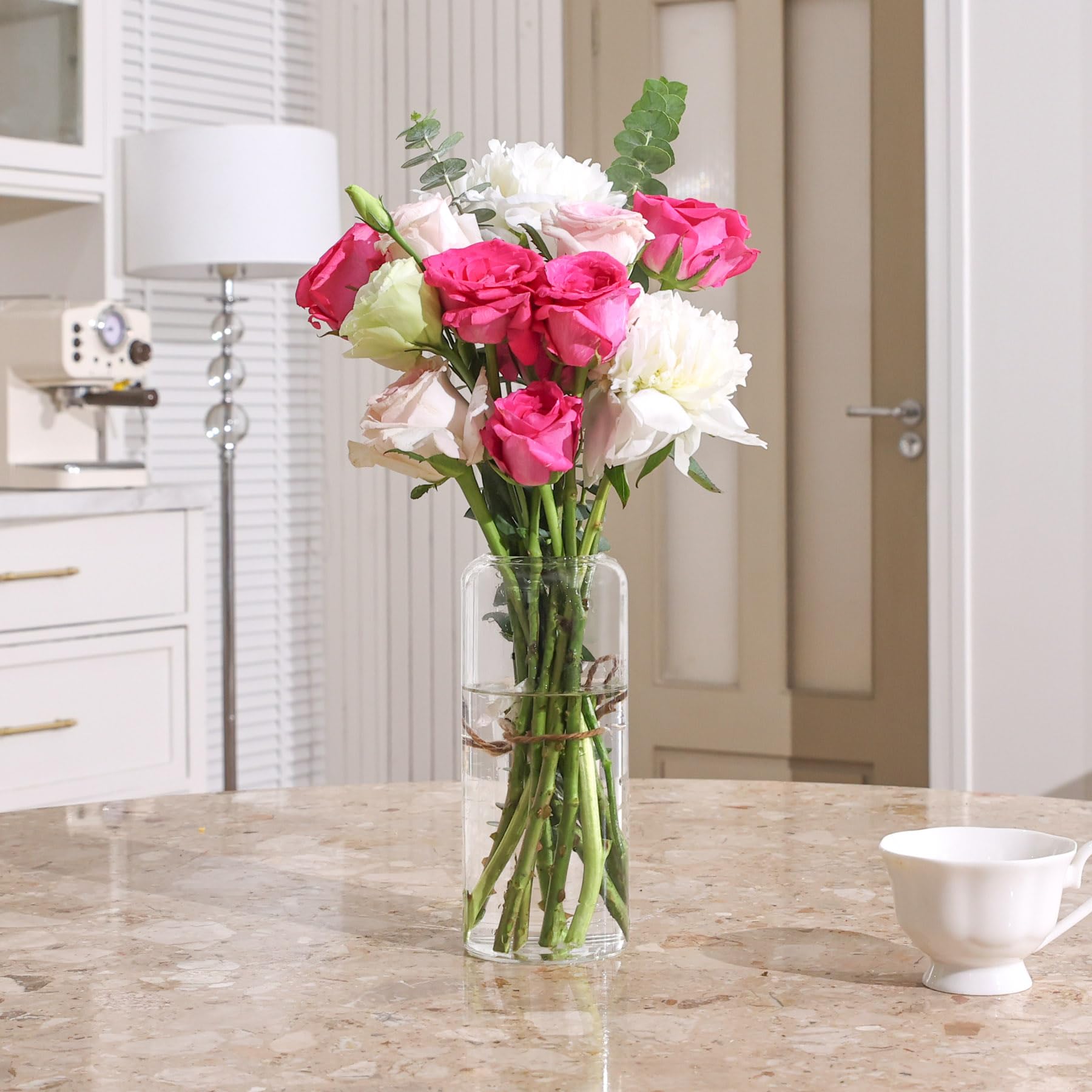 Bouquet of pink, white, and green flowers in a clear vase on a marble surface.