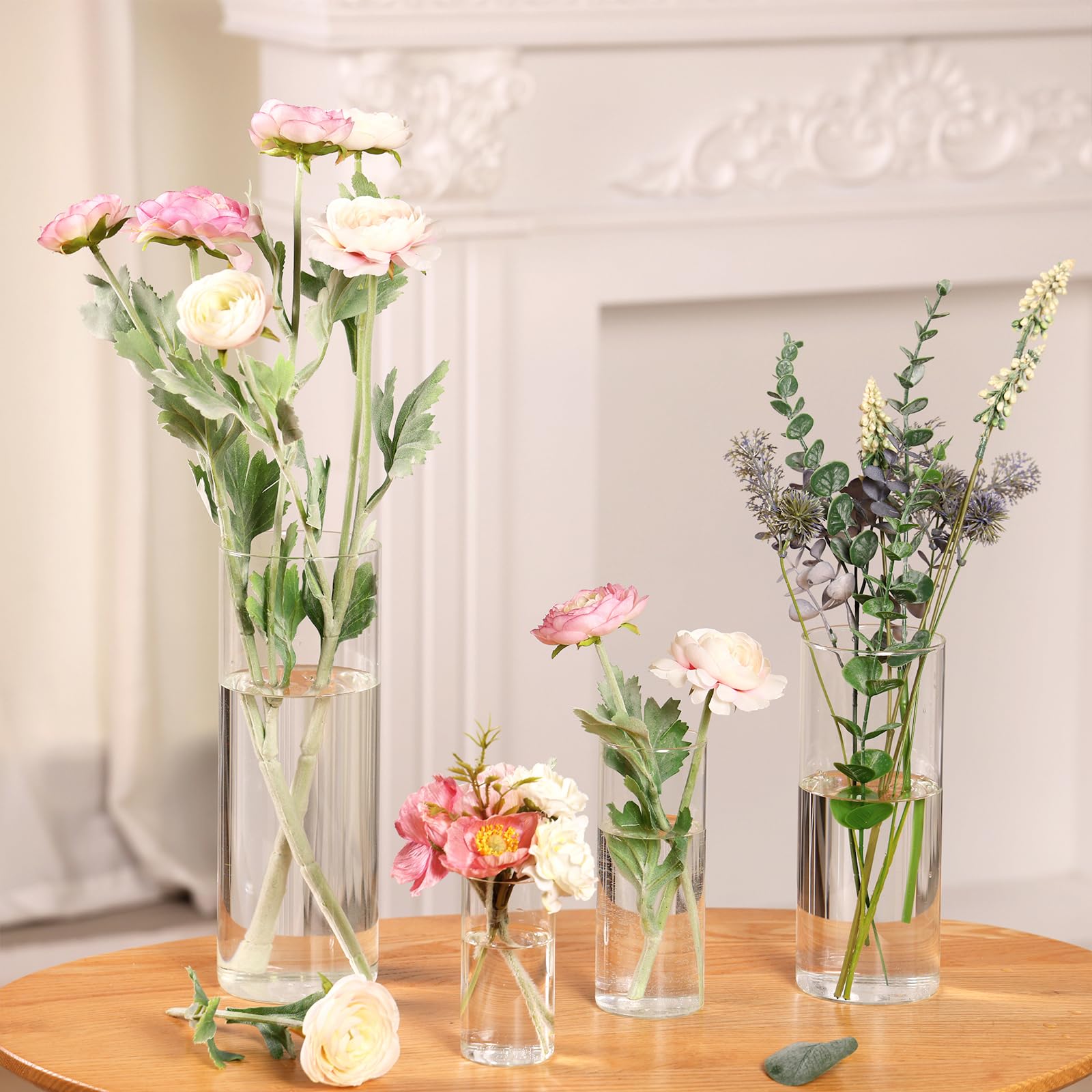 Set of floral arrangements in clear vases on a wooden table with a neutral background