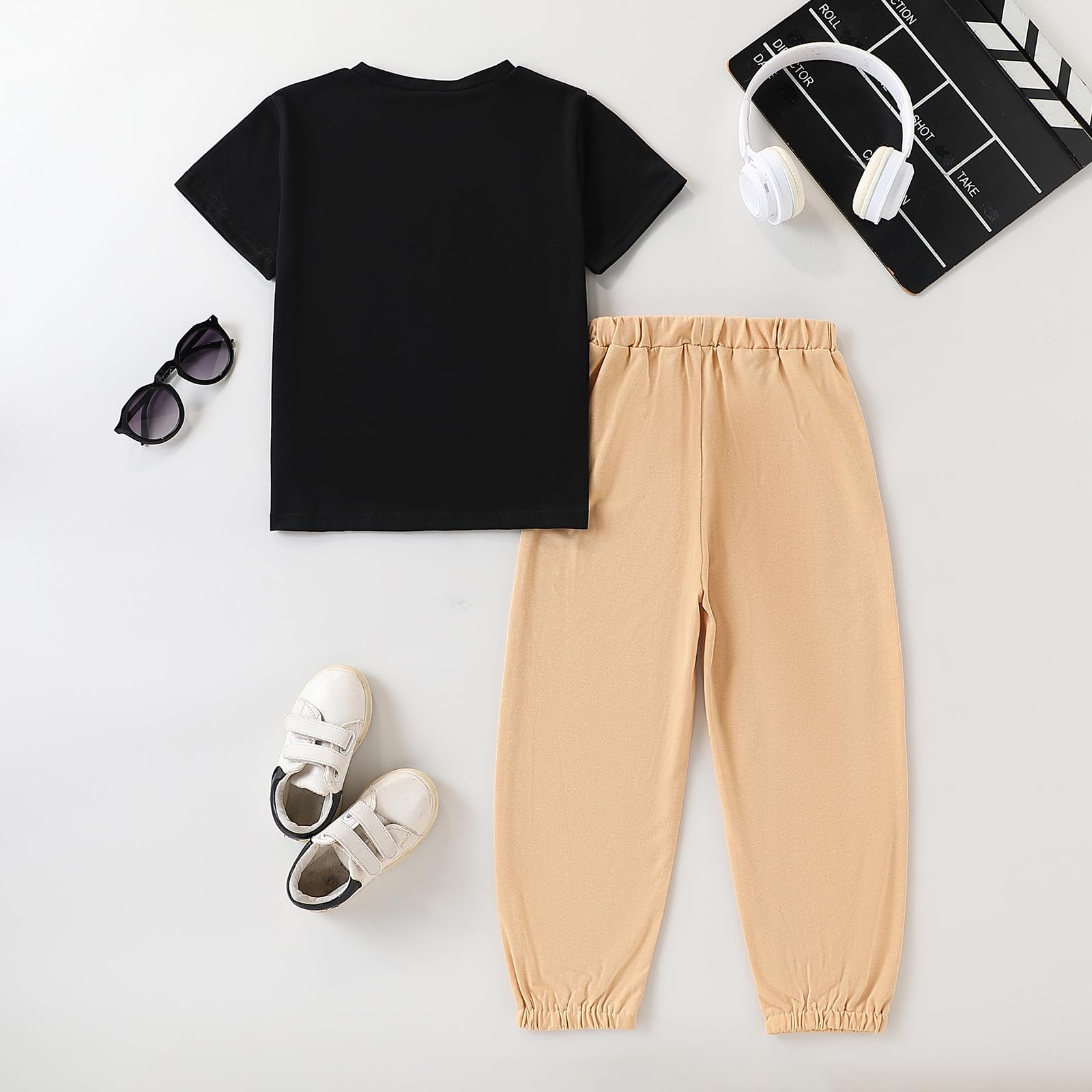 Black t-shirt, beige pants, white sneakers, sunglasses, and a clapperboard on a white background