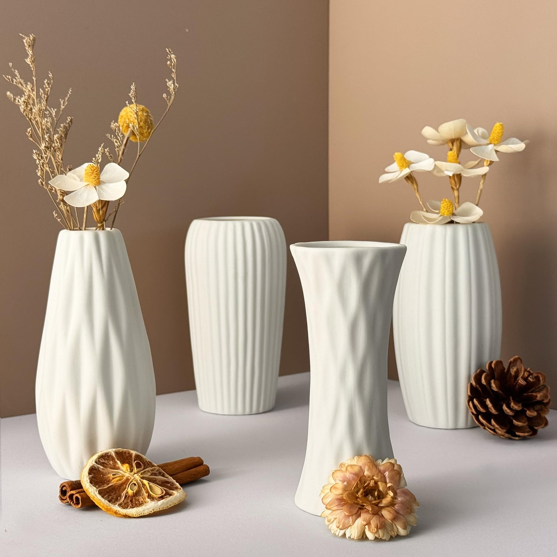 Set of white textured vases with floral arrangements on a neutral background