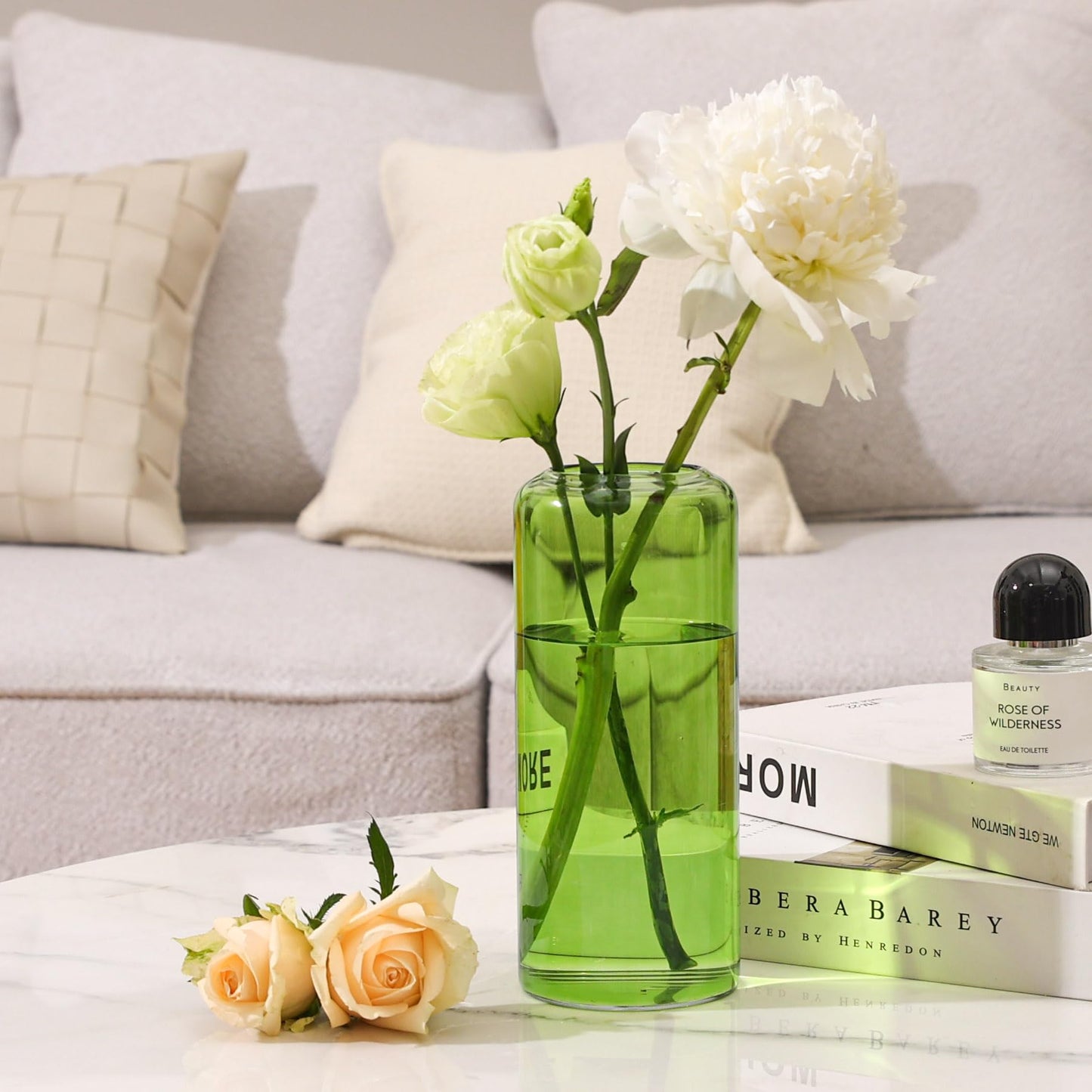 Green vase with flowers on a coffee table in a living room setting
