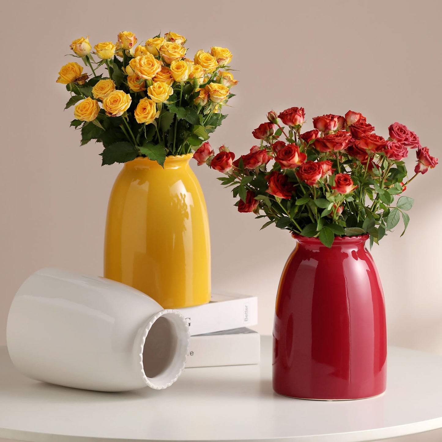 Two vases with yellow and red flowers on a white surface with a beige background