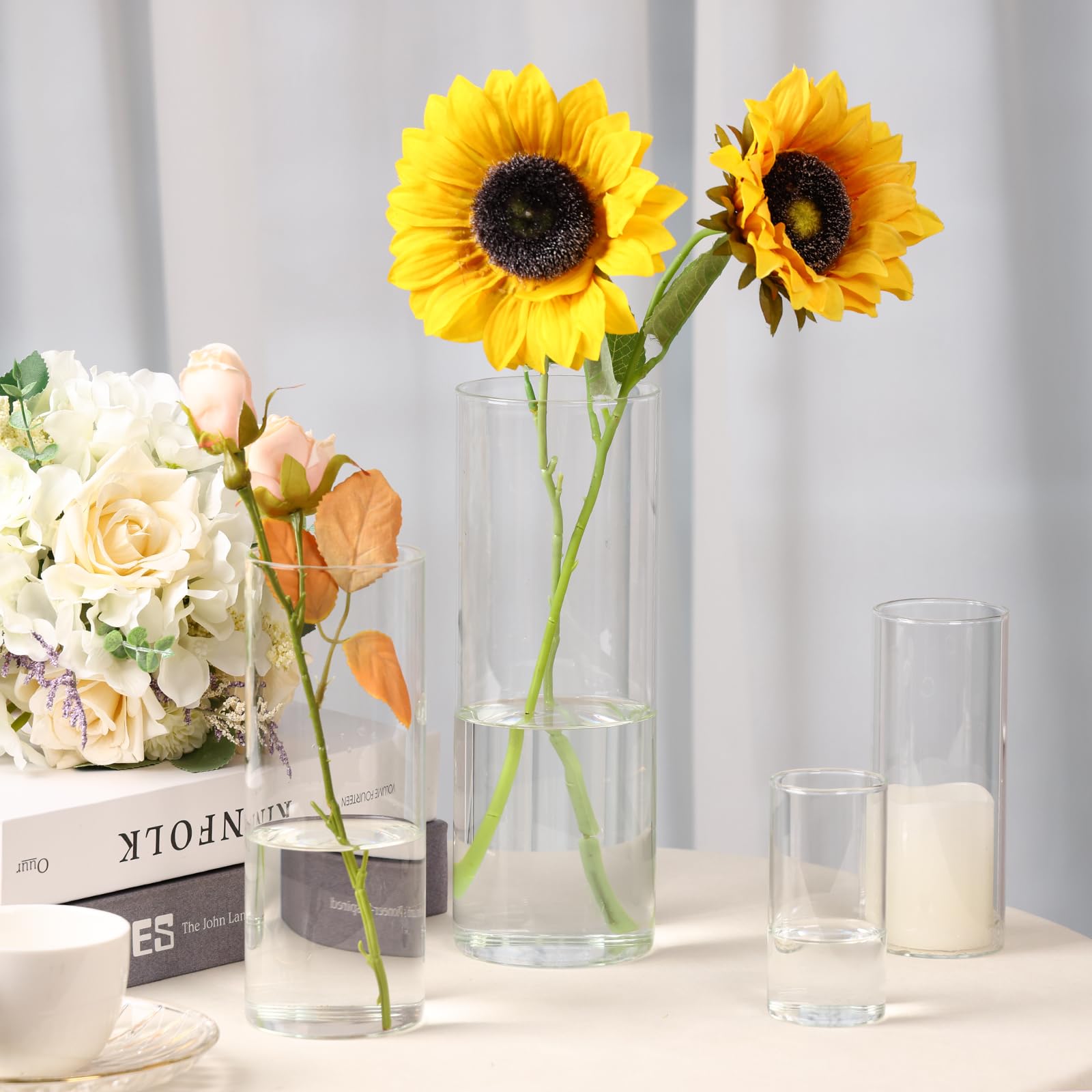Two sunflowers in clear vases on a table with a neutral background