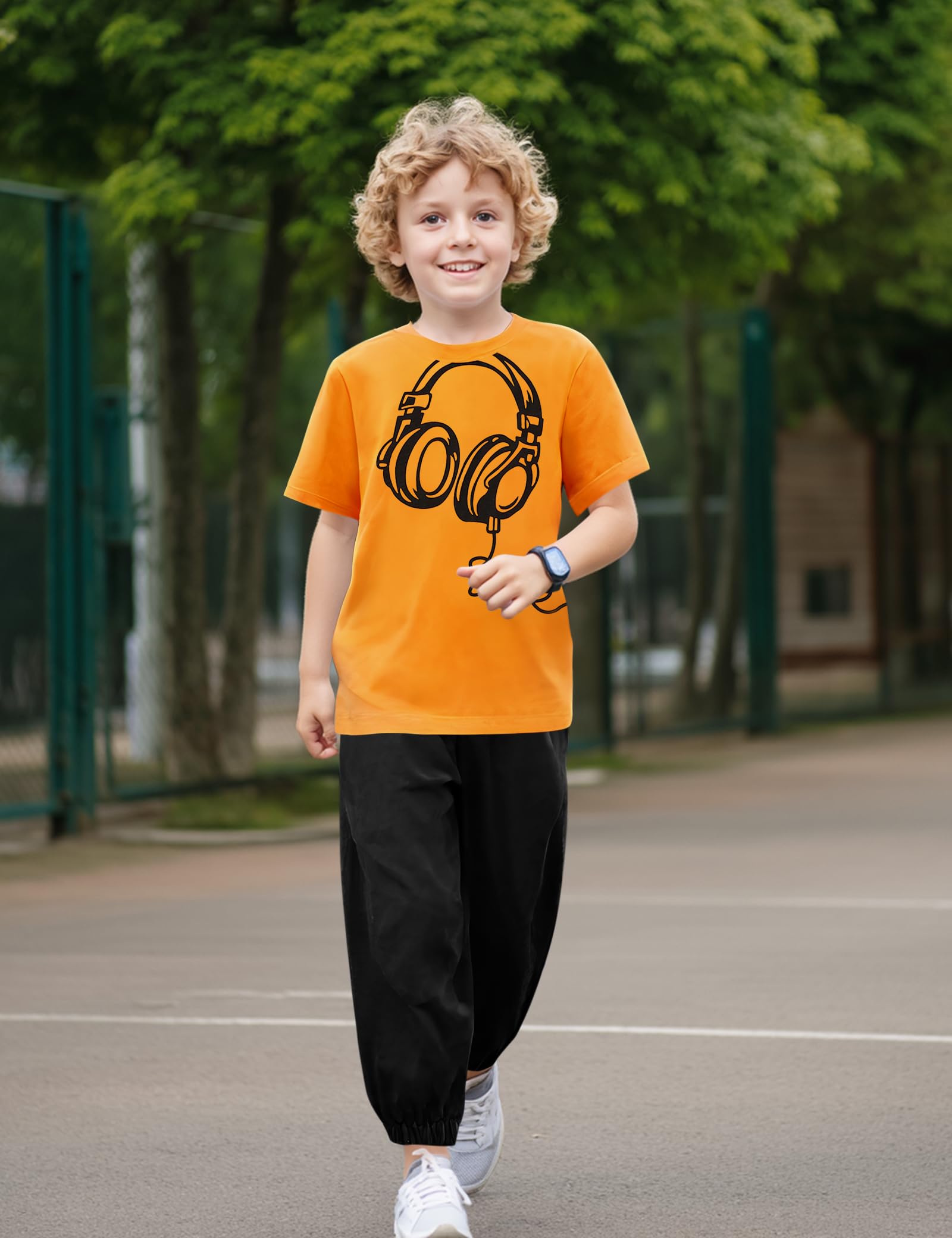 Child wearing an orange t-shirt with a black graphic design outdoors on a playground.