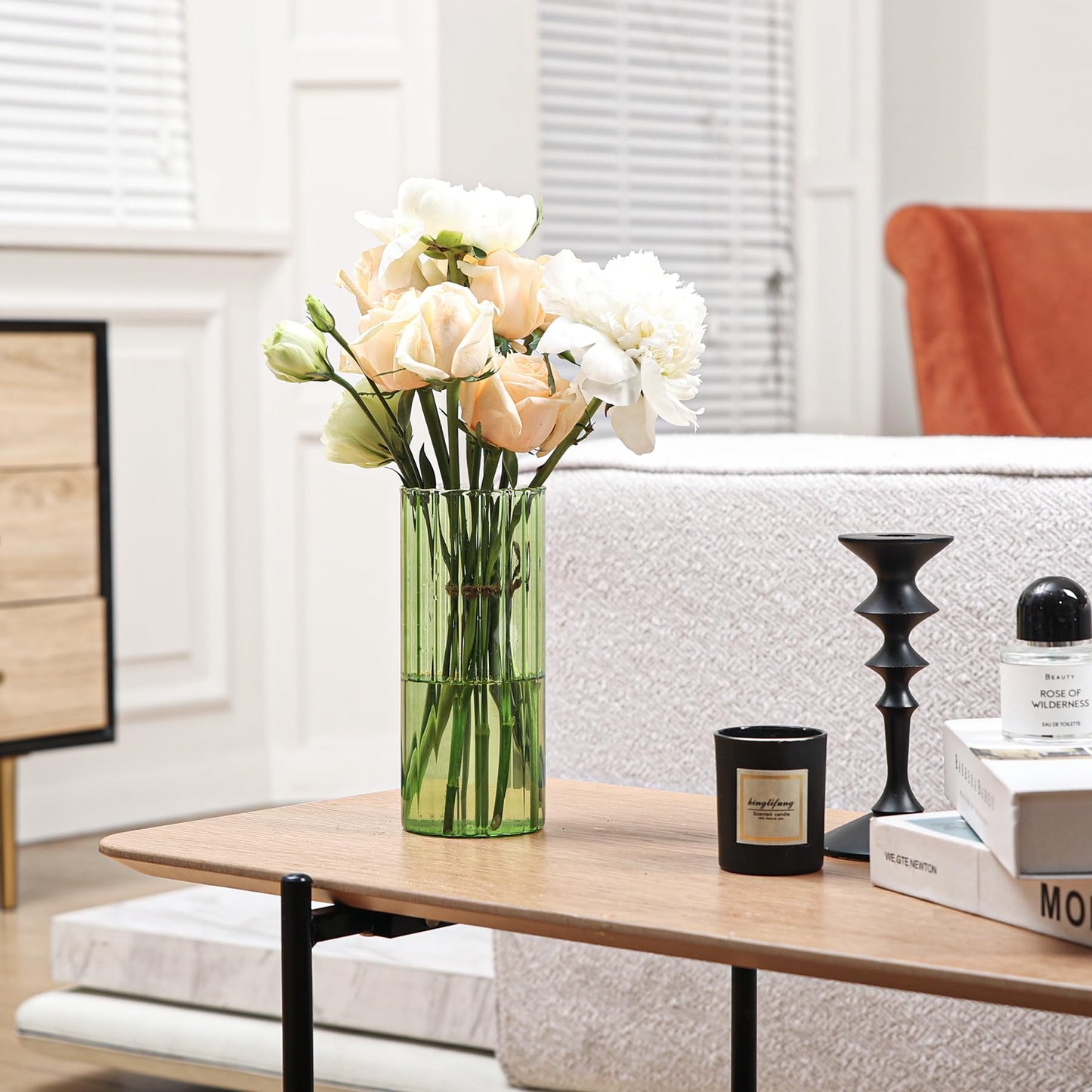 Decorative arrangement with red berries, green leaves, and a vase on a surface.