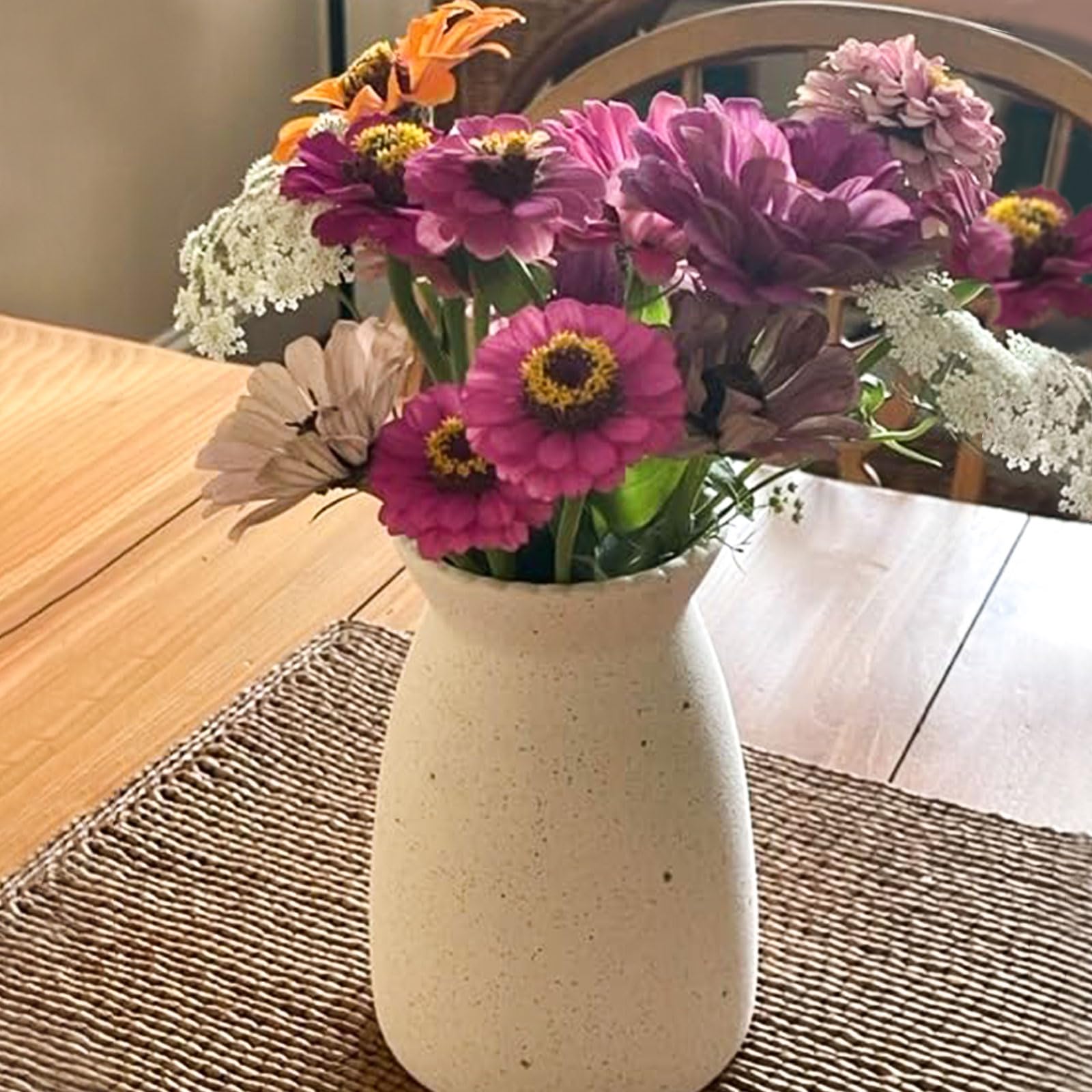 White vase with colorful flowers on a wooden table
