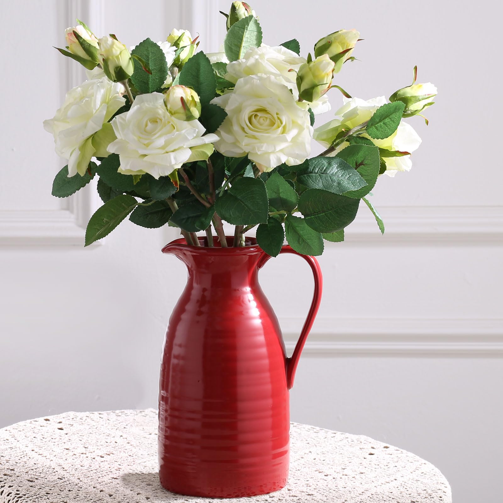 Red vase with white flowers on a textured surface
