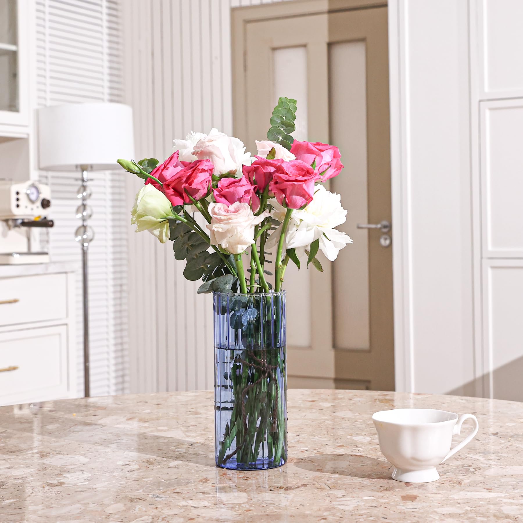 Vase with pink, white, and green flowers on a marble countertop with a white cup.
