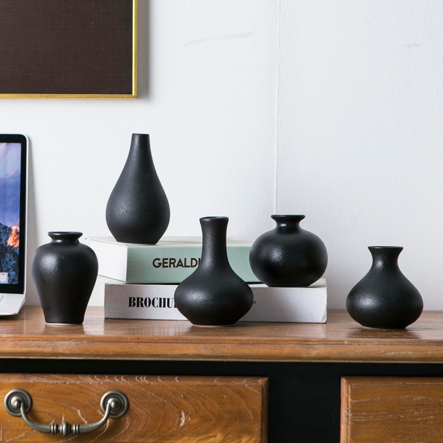 Set of black vases on a wooden surface with books in the background