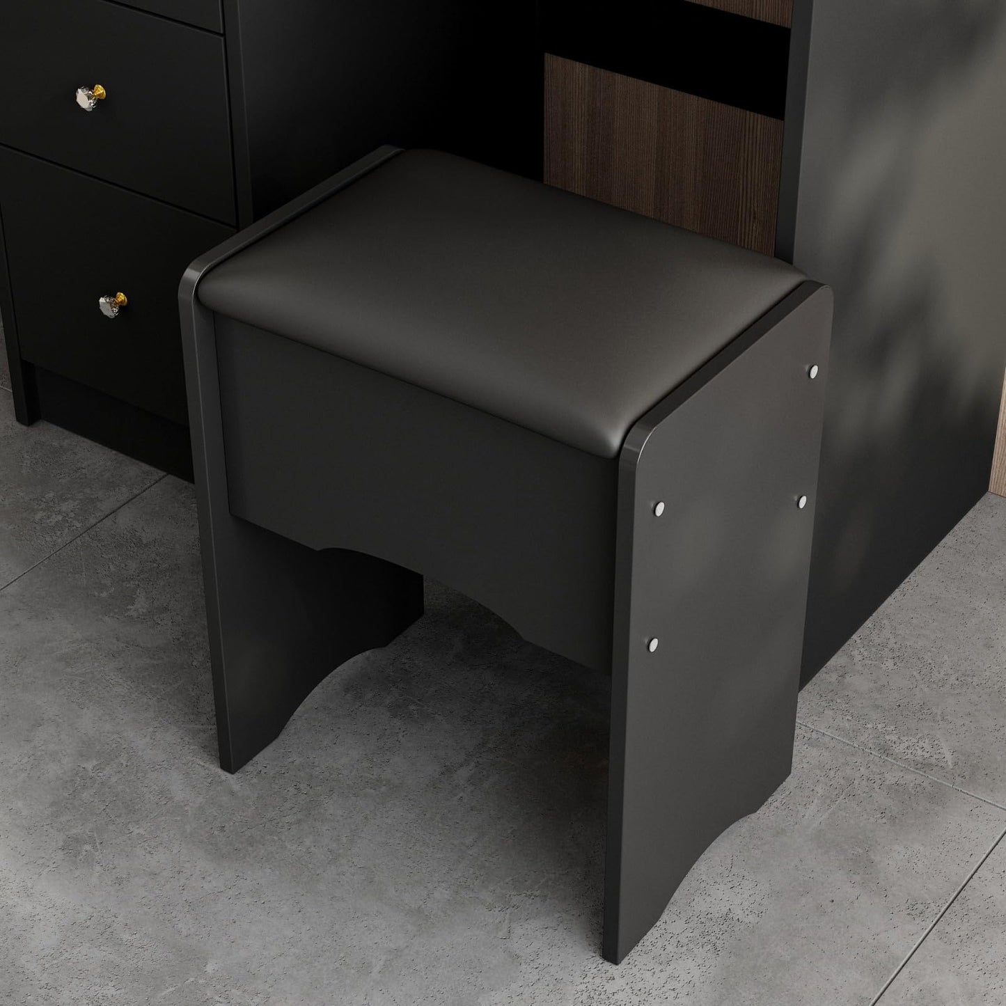 Black stool against a dark wall with a gray floor.