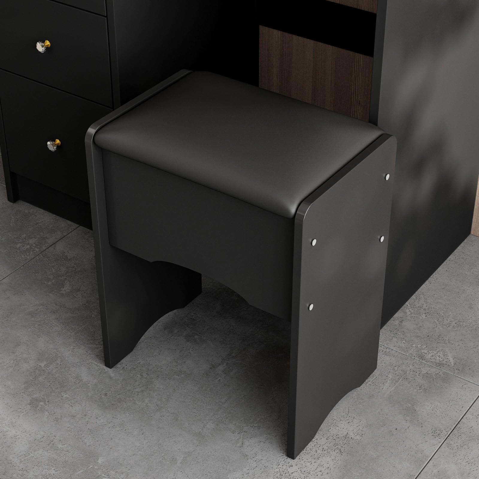 Black stool against a dark wall with a gray floor.