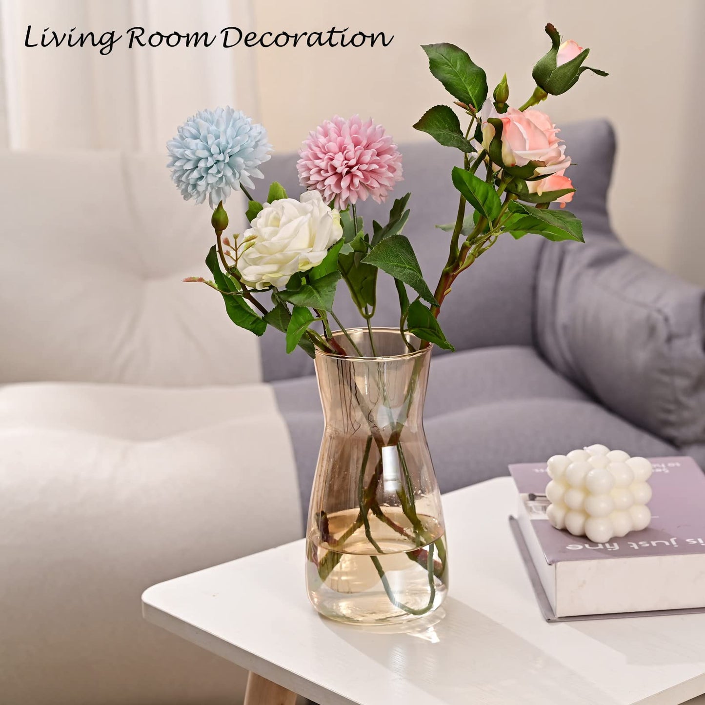 Clear vase with colorful flowers on a white table in a living room setting.
