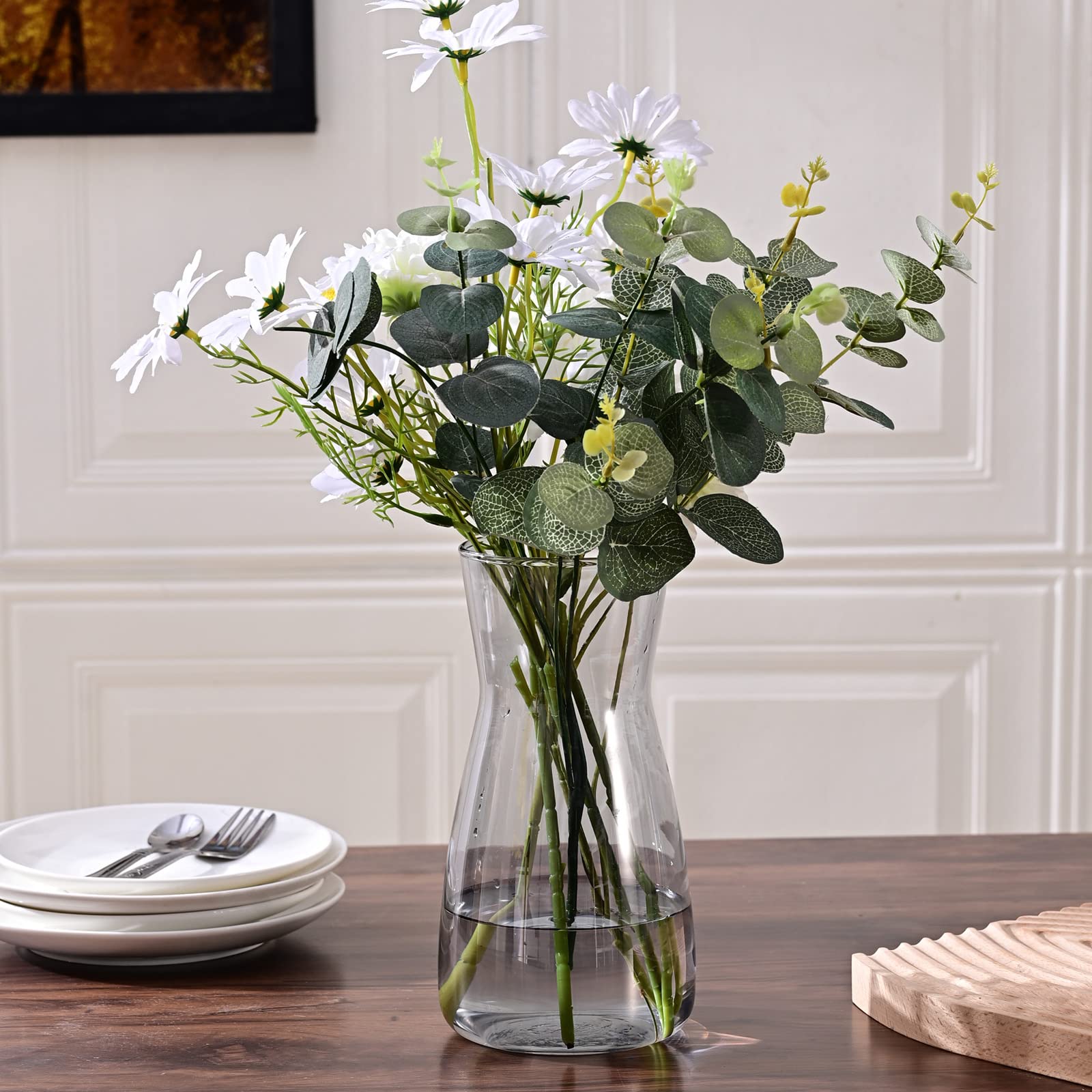 Clear glass vase with artificial flowers on a wooden table