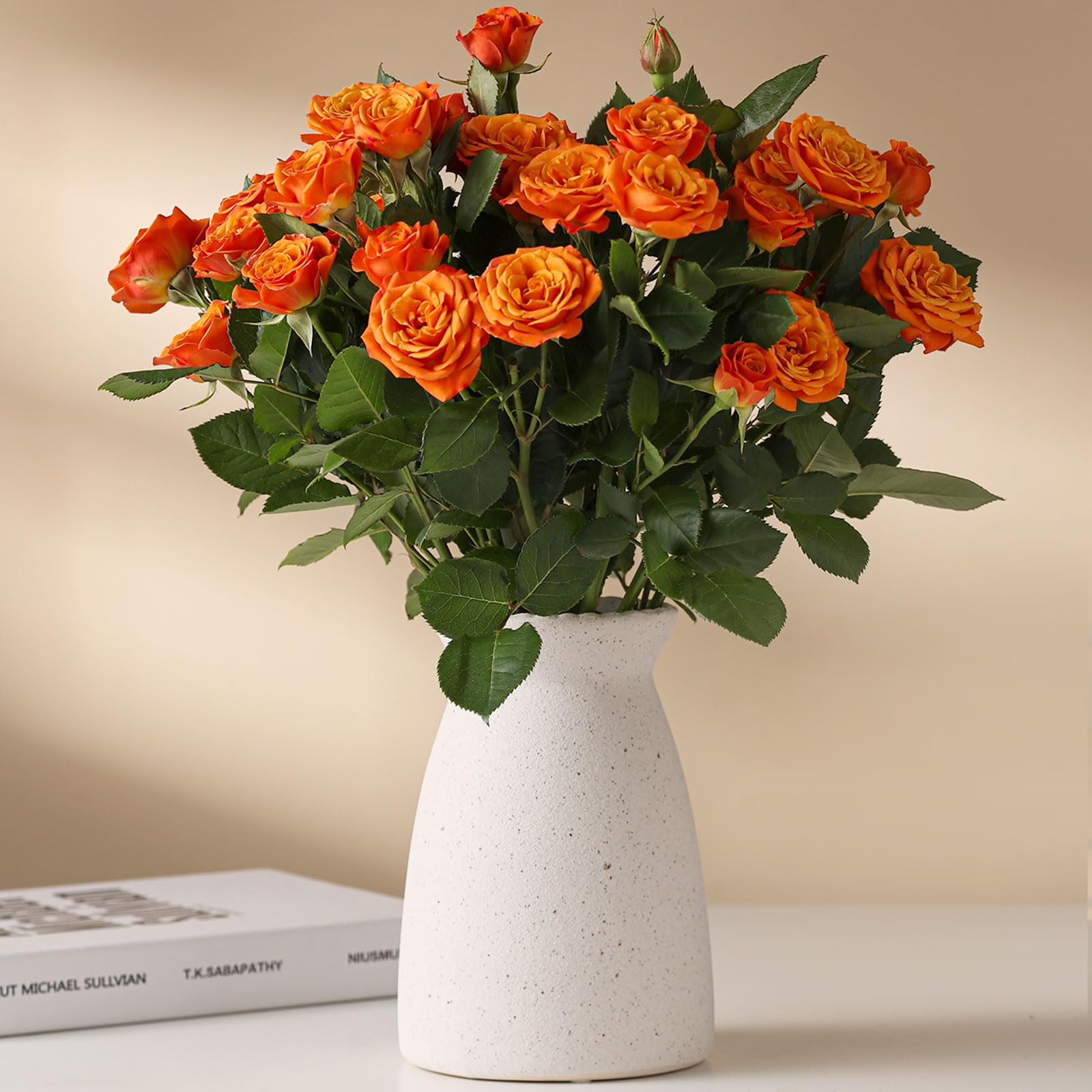 Bouquet of orange roses in a white vase on a light surface with a neutral background