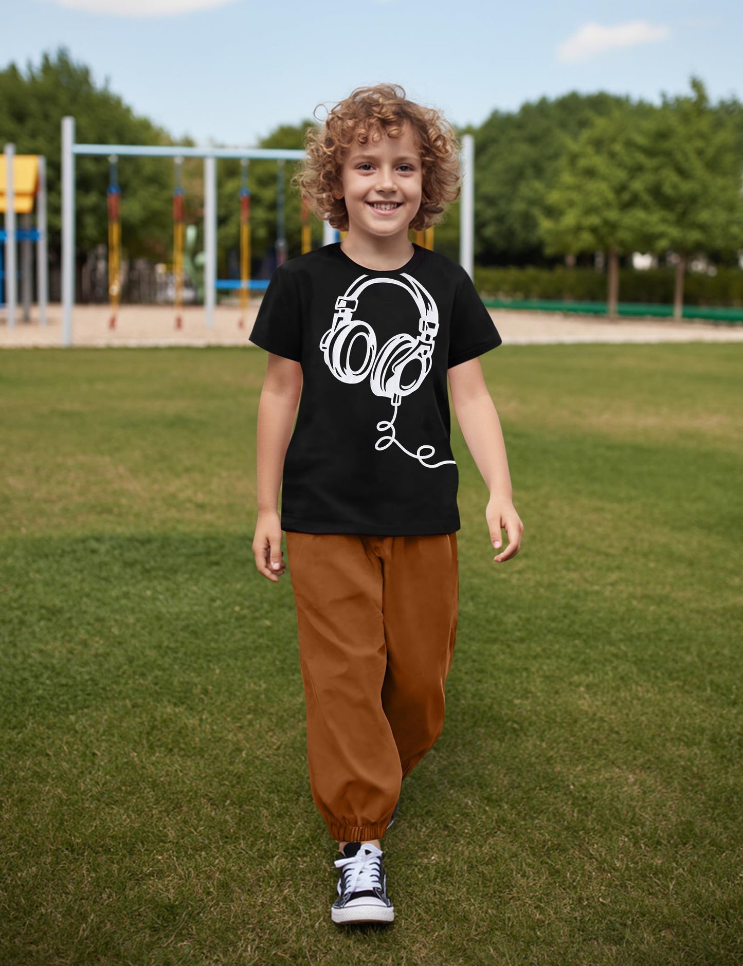 Child wearing a black t-shirt with a white graphic design outdoors on grass