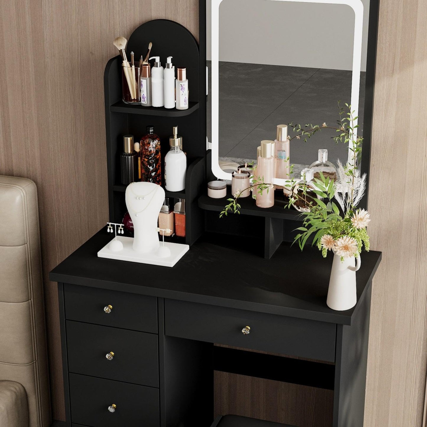 Black vanity table with mirror, drawers, and cosmetic items in a room.