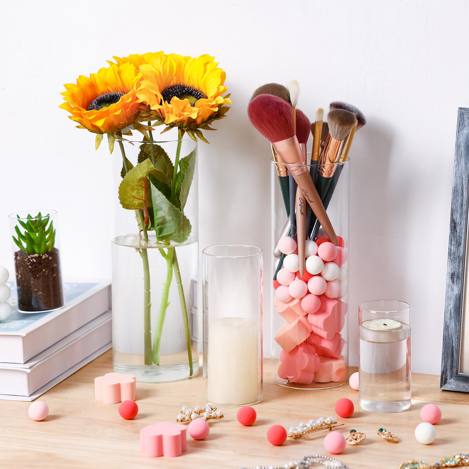 Decorative setup with sunflowers in a vase, makeup brushes, candles, and small decorative items on a wooden surface.
