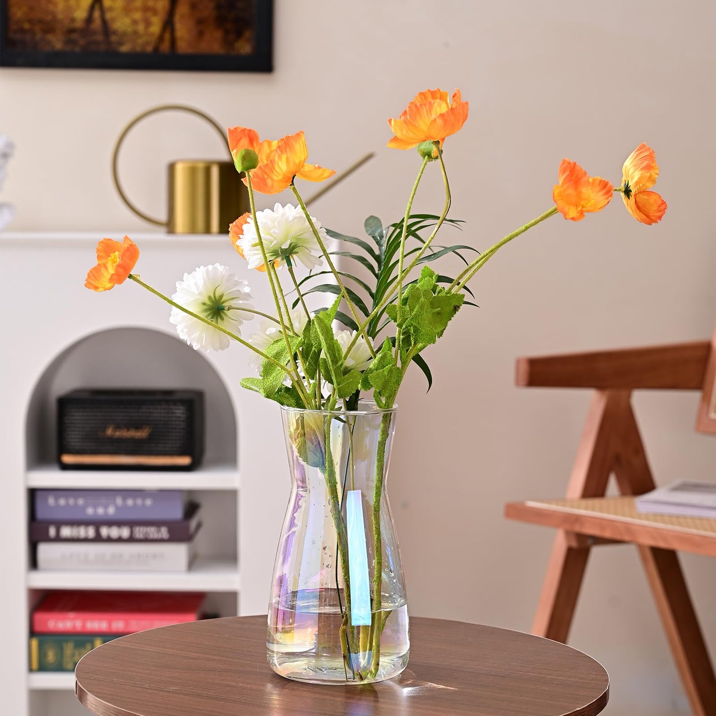 Clear vase with orange and white flowers on a wooden table in a room setting.