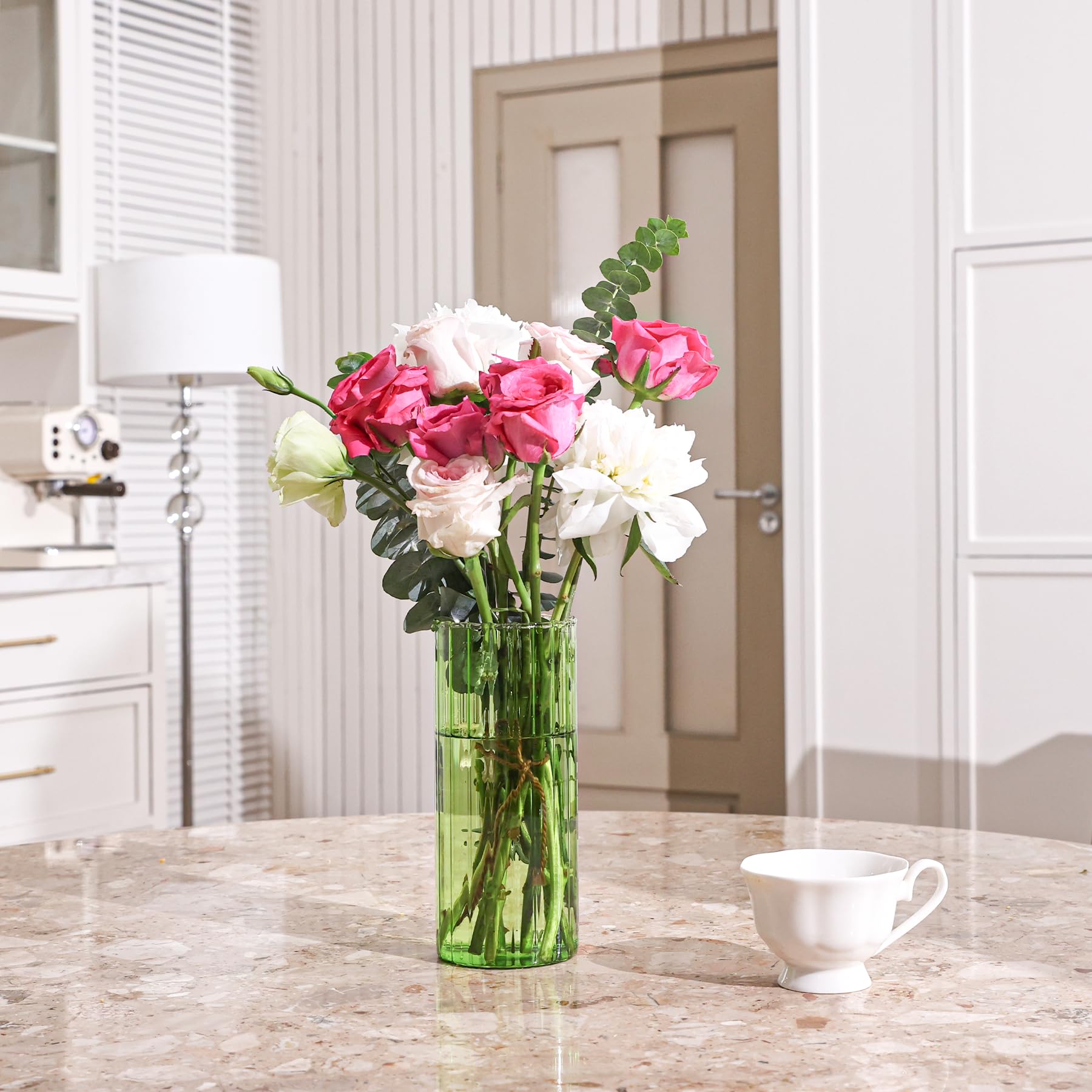 Decorative arrangement with red berries, green leaves, and a vase on a surface.