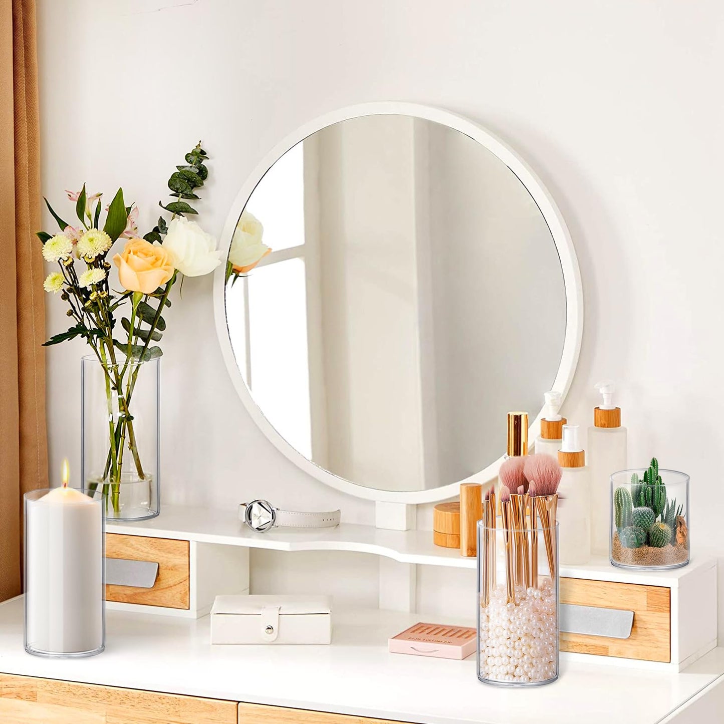Round mirror on a vanity with decorative items including candles, flowers, and small plants.