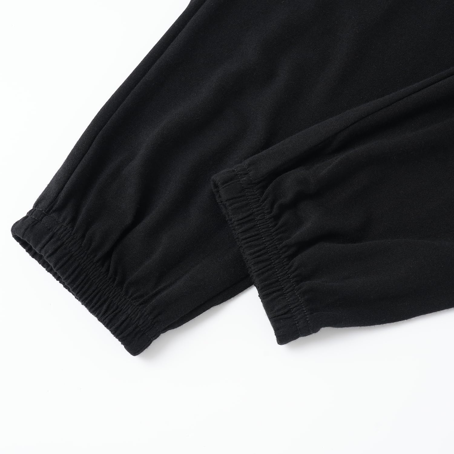 Close-up of black pants with elastic cuffs on a white background
