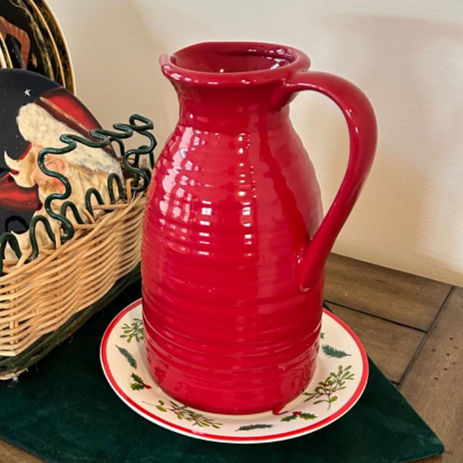 Red ceramic pitcher on a decorative plate with a wicker basket in the background