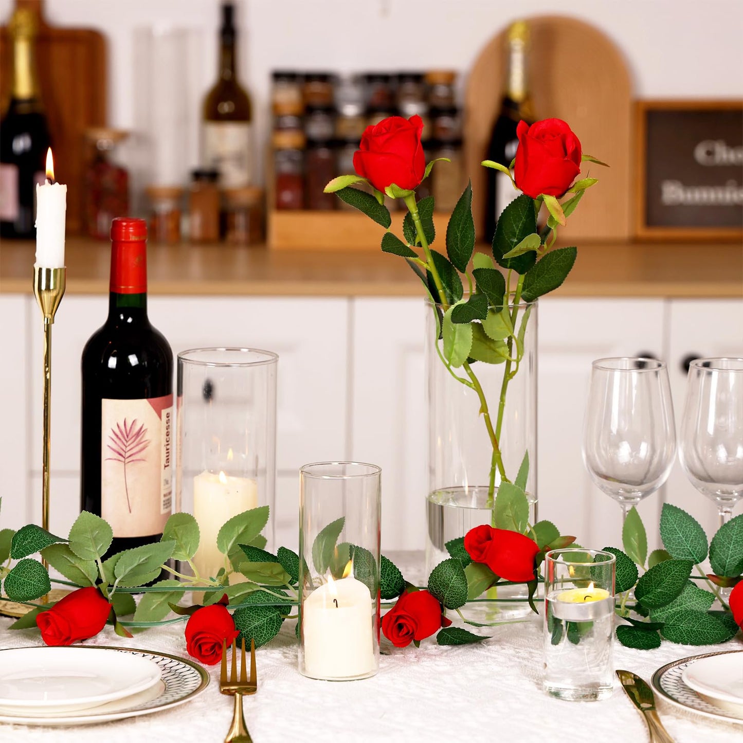 Dining table set for a romantic dinner with red roses, candles, and wine.