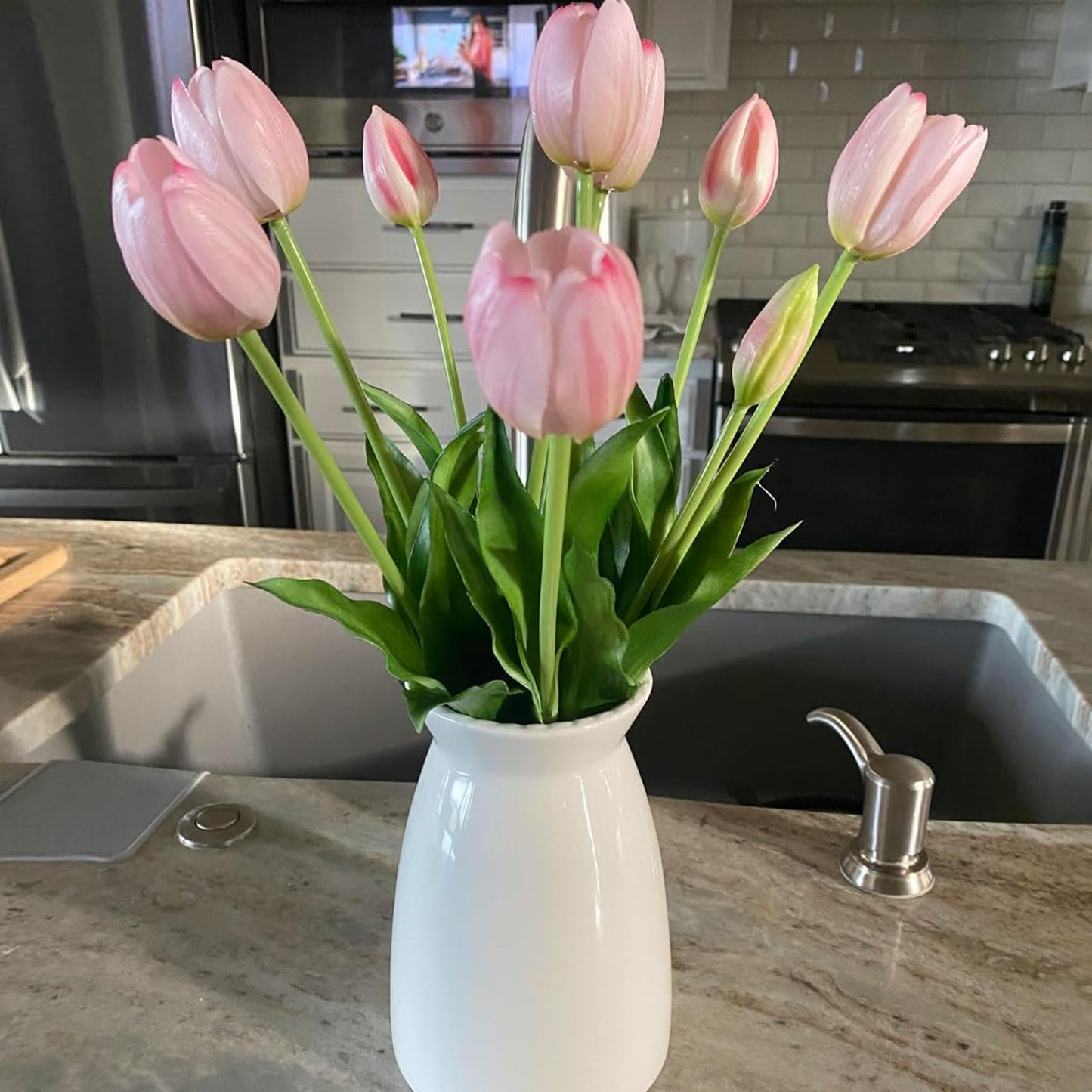 White vase with pink tulips on a kitchen counter