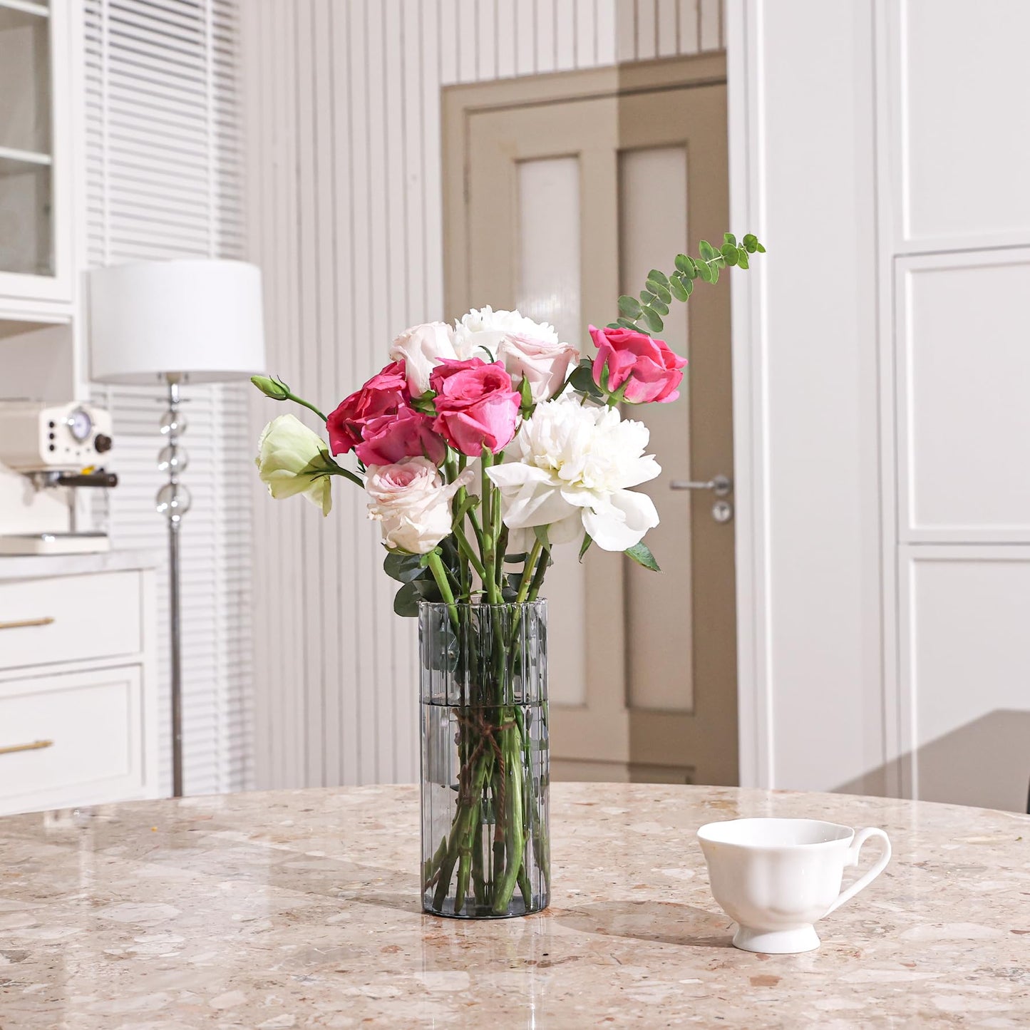 Vase with pink and white flowers on a marble countertop in a kitchen.